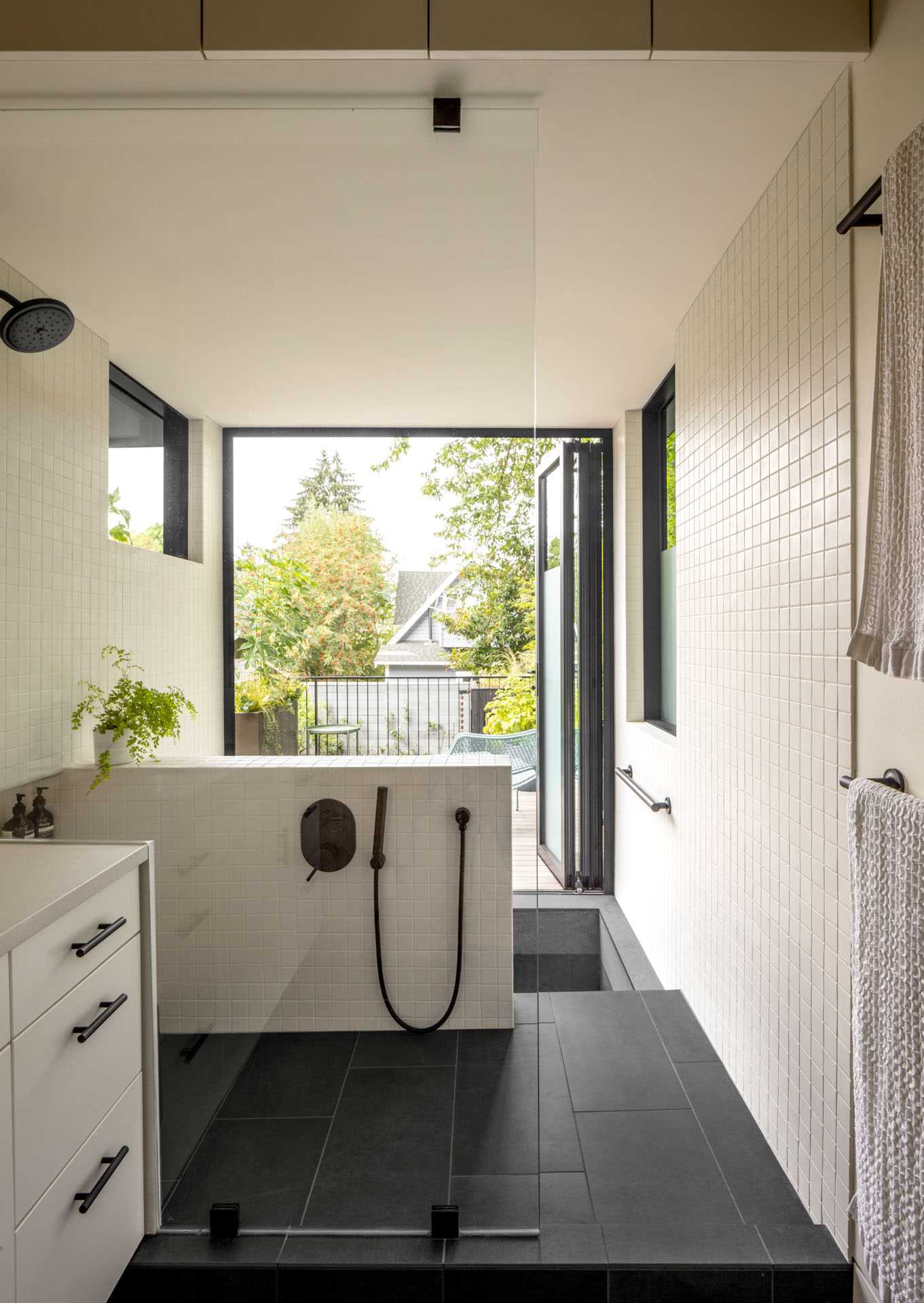 A modern family bathroom includes a traditional Japanese soaking tub (Ofuro), directly connecting to the outdoors via a folding glass door. A separate toilet room increases comfort and usability for the young family.