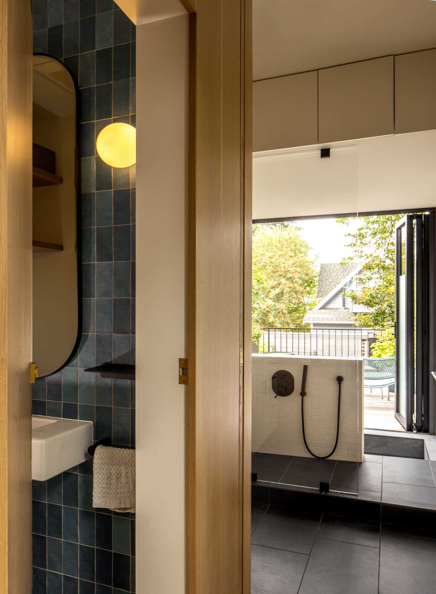 A modern family bathroom includes a traditional Japanese soaking tub (Ofuro), directly connecting to the outdoors via a folding glass door. A separate toilet room increases comfort and usability for the young family.