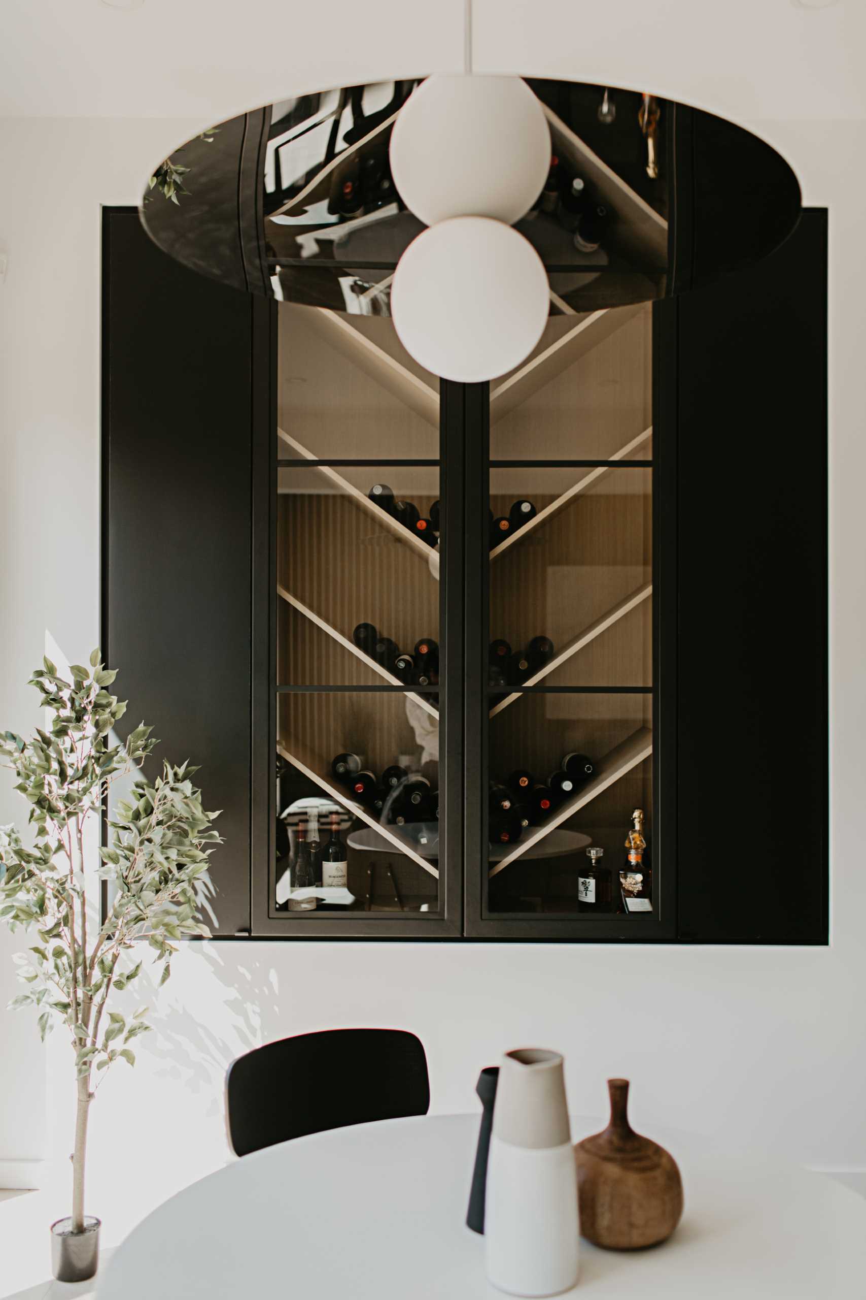 A wine rack with shelves angled in a chevron pattern creates an interesting focal point to this dining area, while a round table is positioned below the minimalist pendant light.