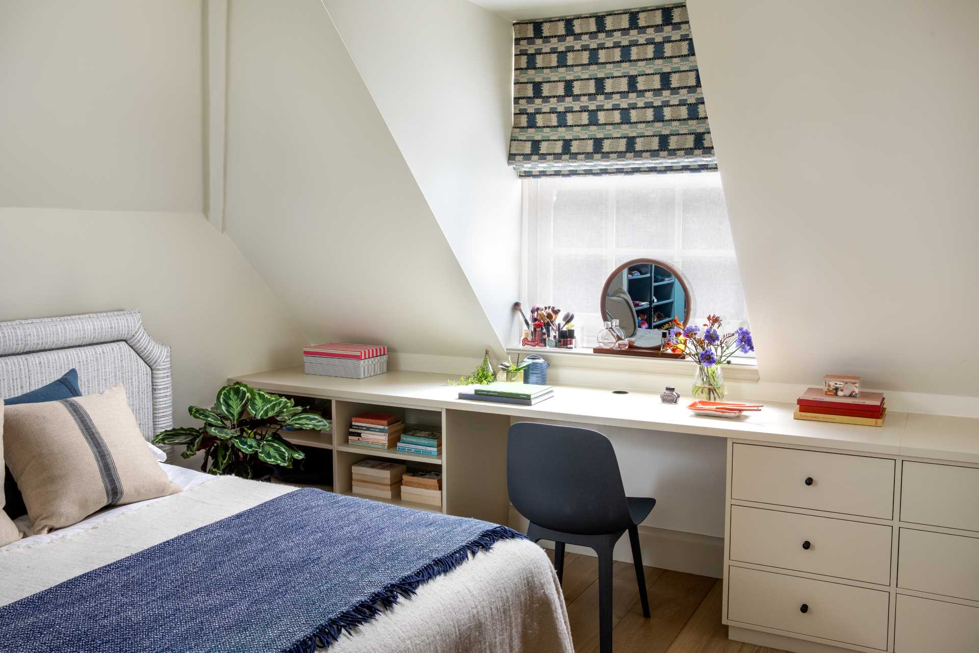 In this bedroom, there's a built-in desk by the window that incorporates drawers and open shelves.