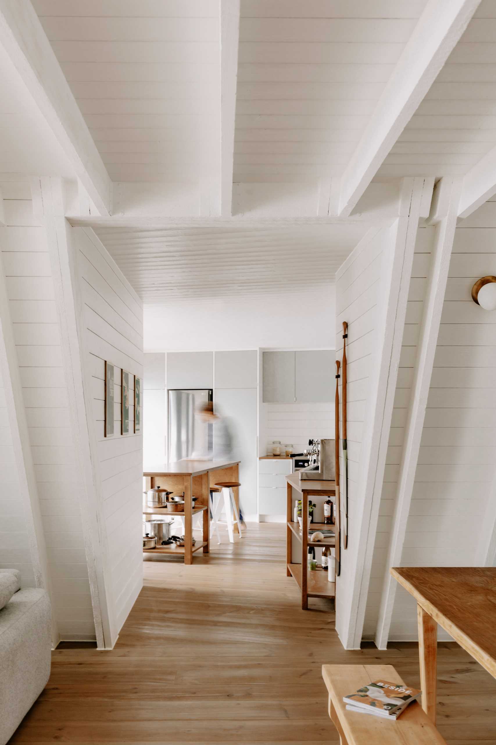 Modern kitchen inside an updated A-Frame cabin with a white interior and wood floors.