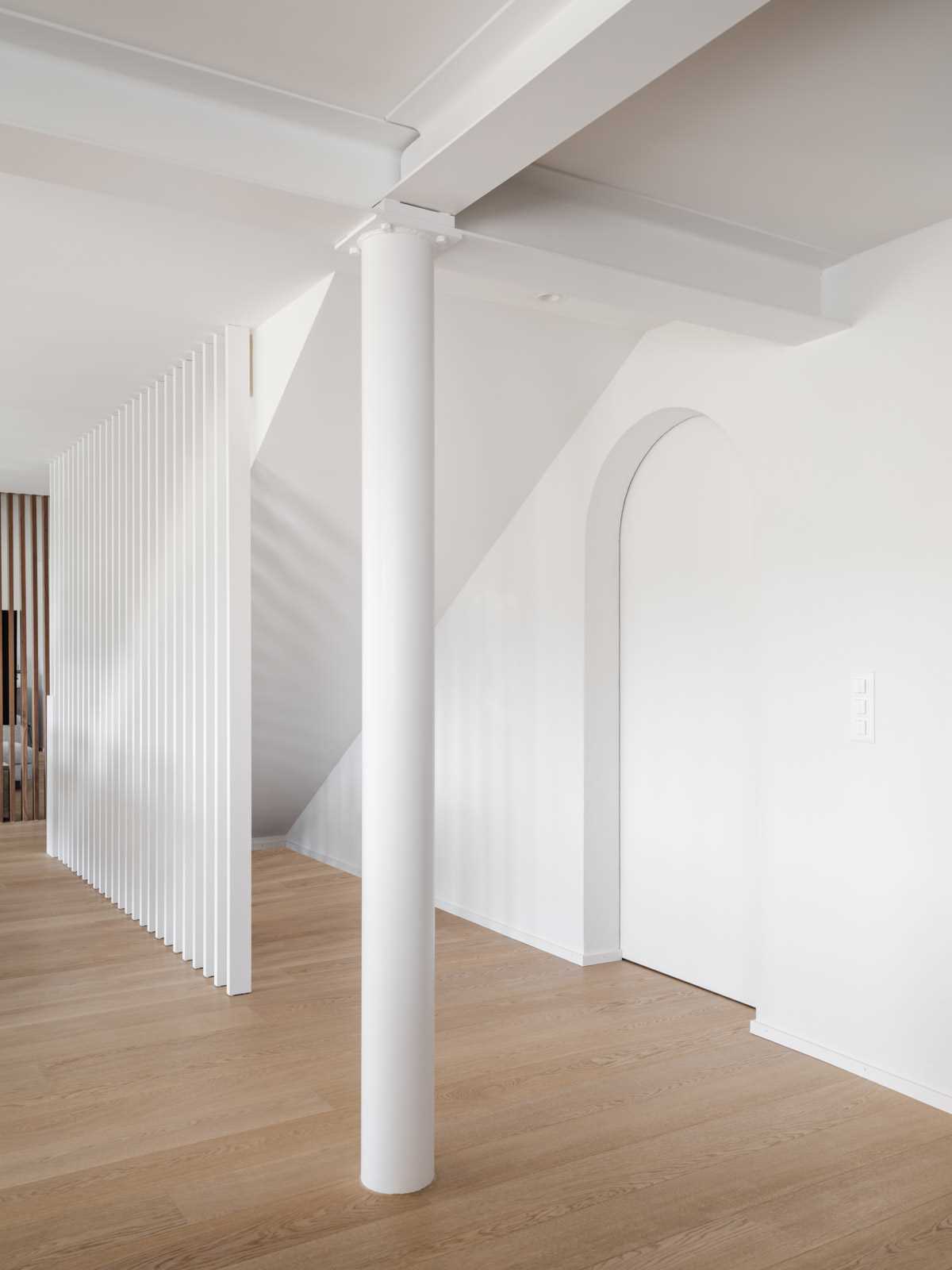 An arched doorway almost blends into its surrounds under the stairs.