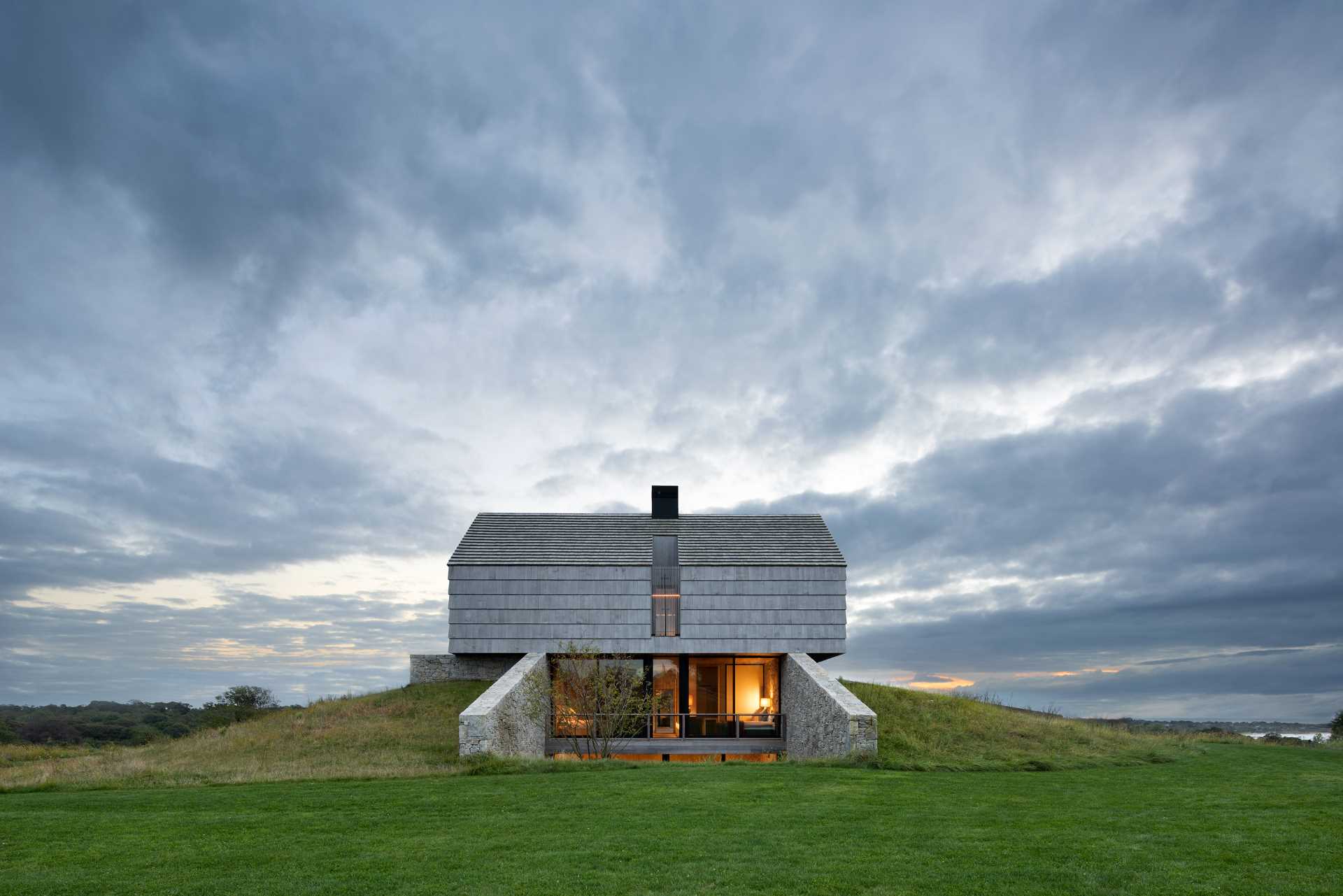 A modern home with two stone and shingle "cottages" connected by an open living room, dining area, and kitchen.