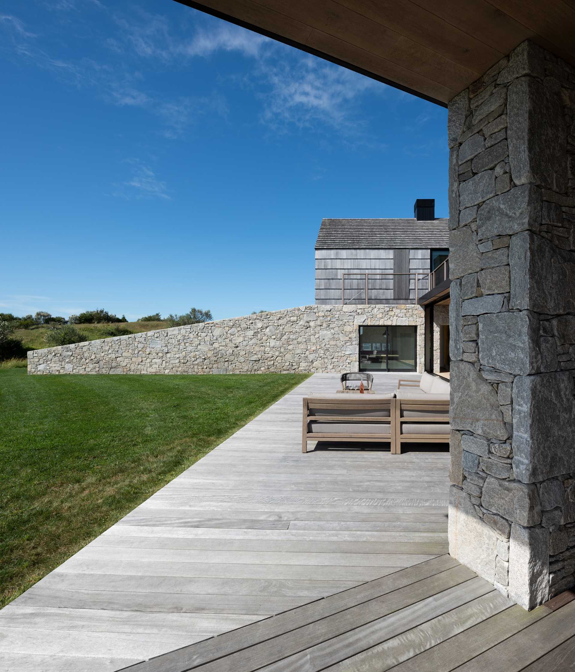 A modern home with two stone and shingle "cottages" connected by an open living room, dining area, and kitchen.