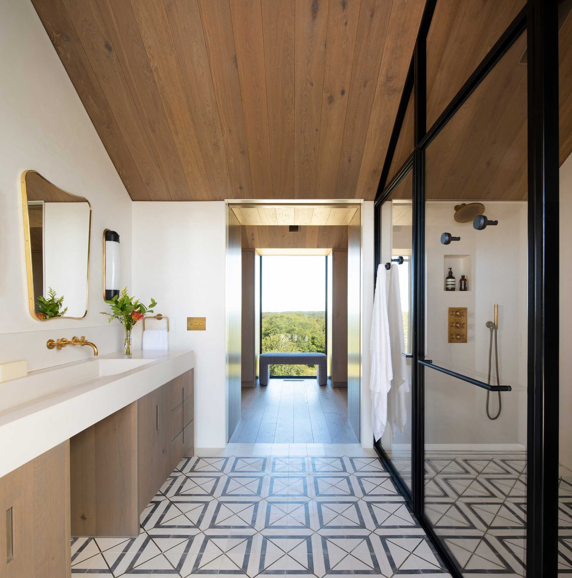 In this modern bathroom, the thick black frames of the shower complement the black window frames found throughout the home.