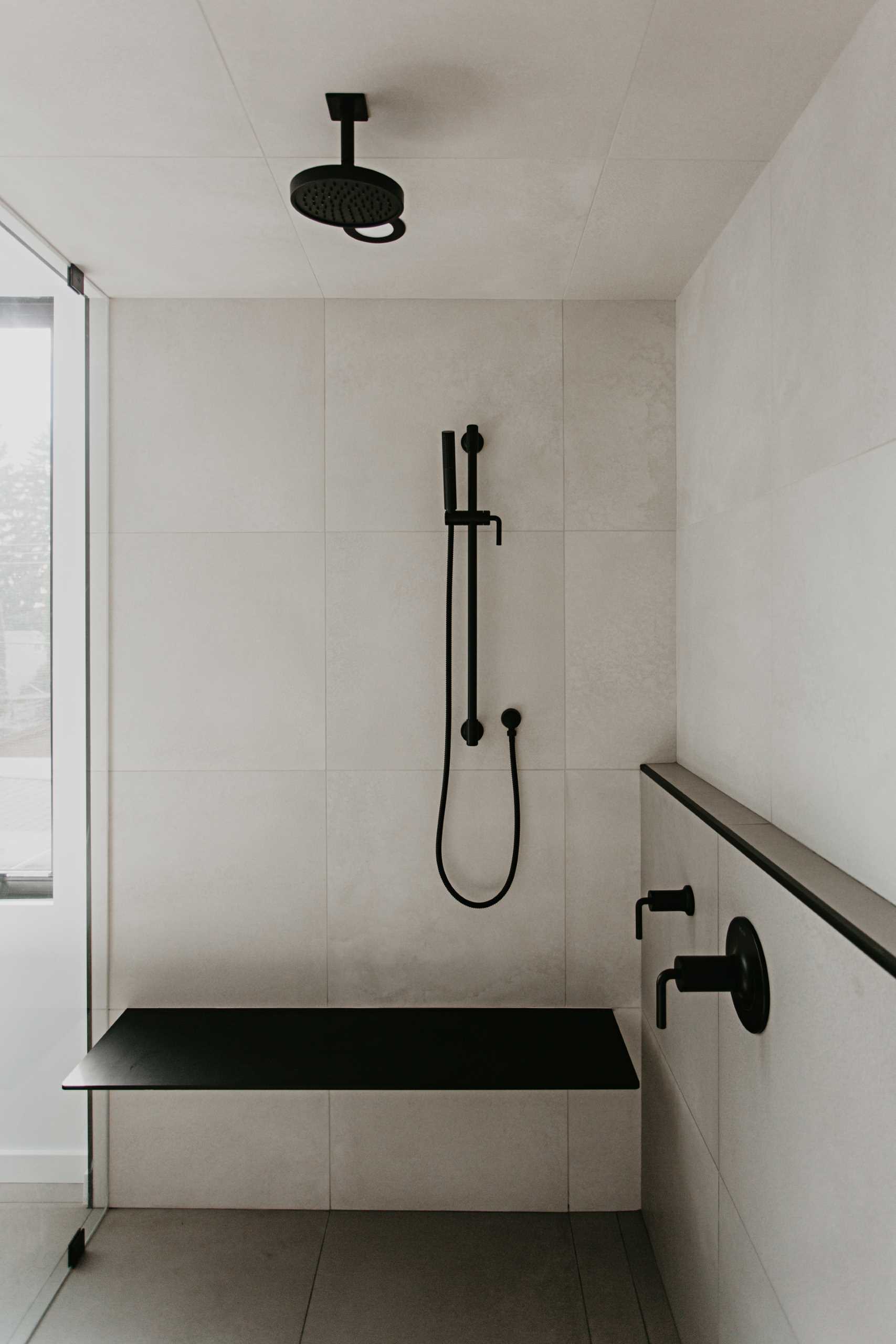 A walk-in shower with black details, a bench, and a shelf.