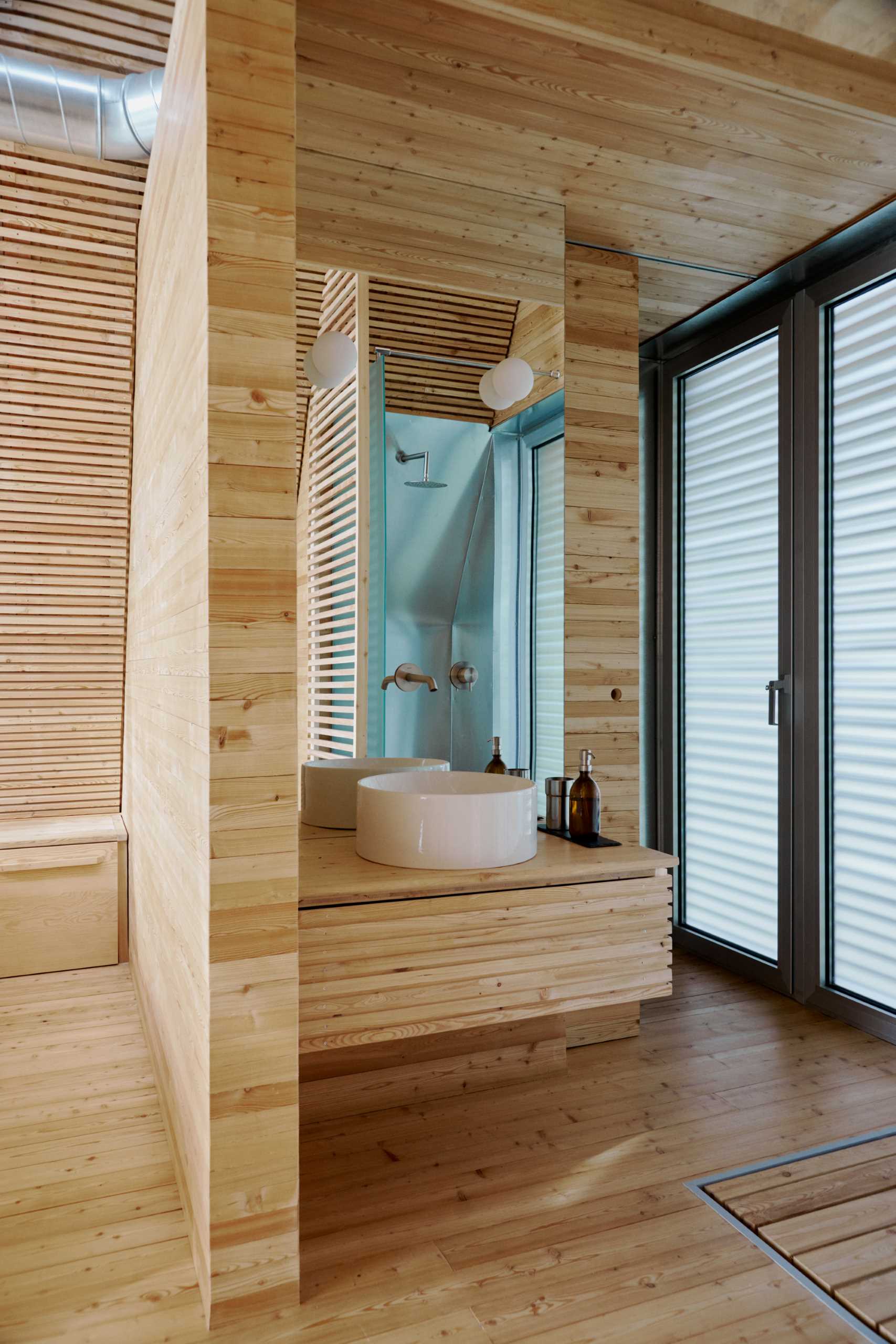 The minimal bathrooms include a simple wood vanity with a tall mirror and a walk-in shower.