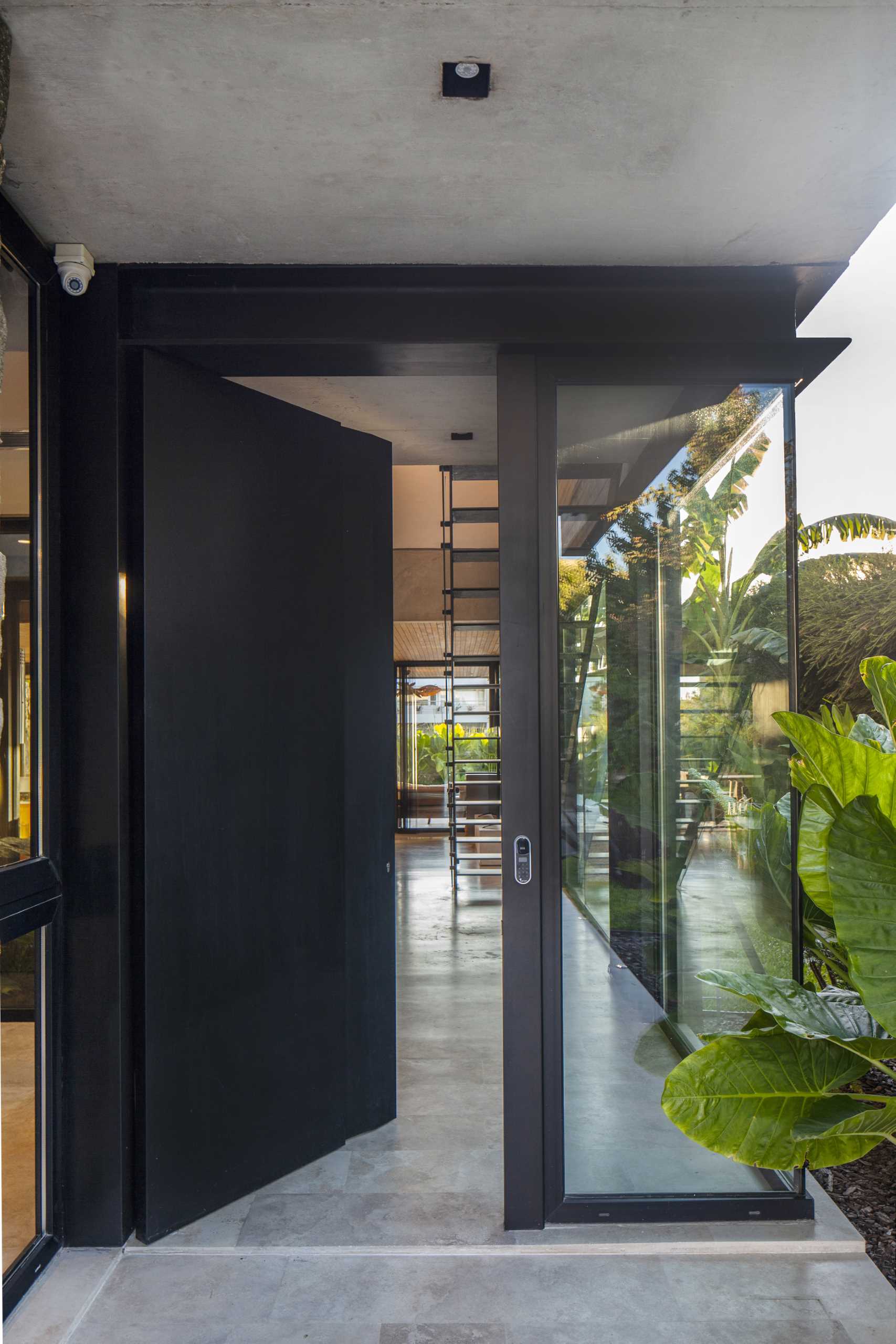 A modern home with a black front door that has windows on either side to provide a glimpse of the interior.