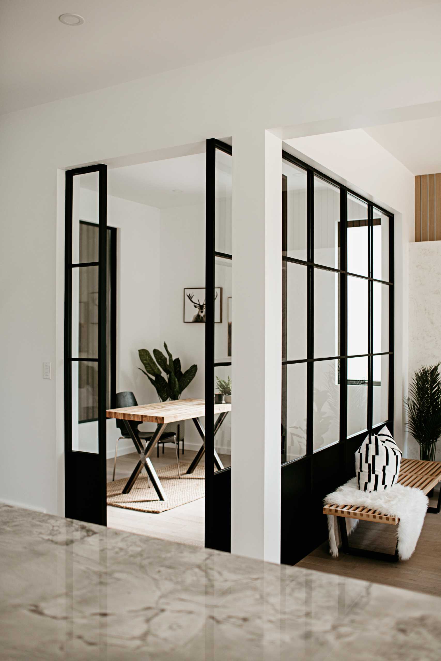 Windows with thick black frames and a pivoting door enclose the home office, and at the same time, complement the black in the kitchen.