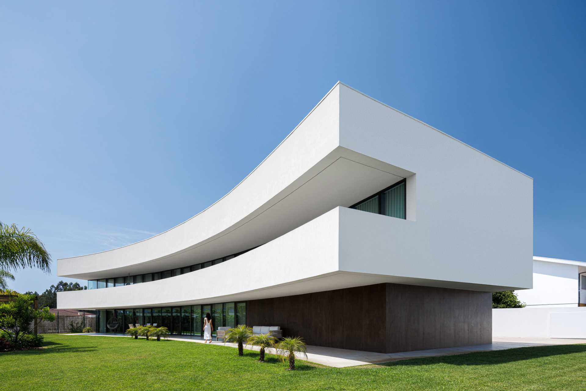 Through its shape and arrangement, this curved home protects itself from the busy road, while also opening up the interior to the outdoor spaces, like the yard and balcony.