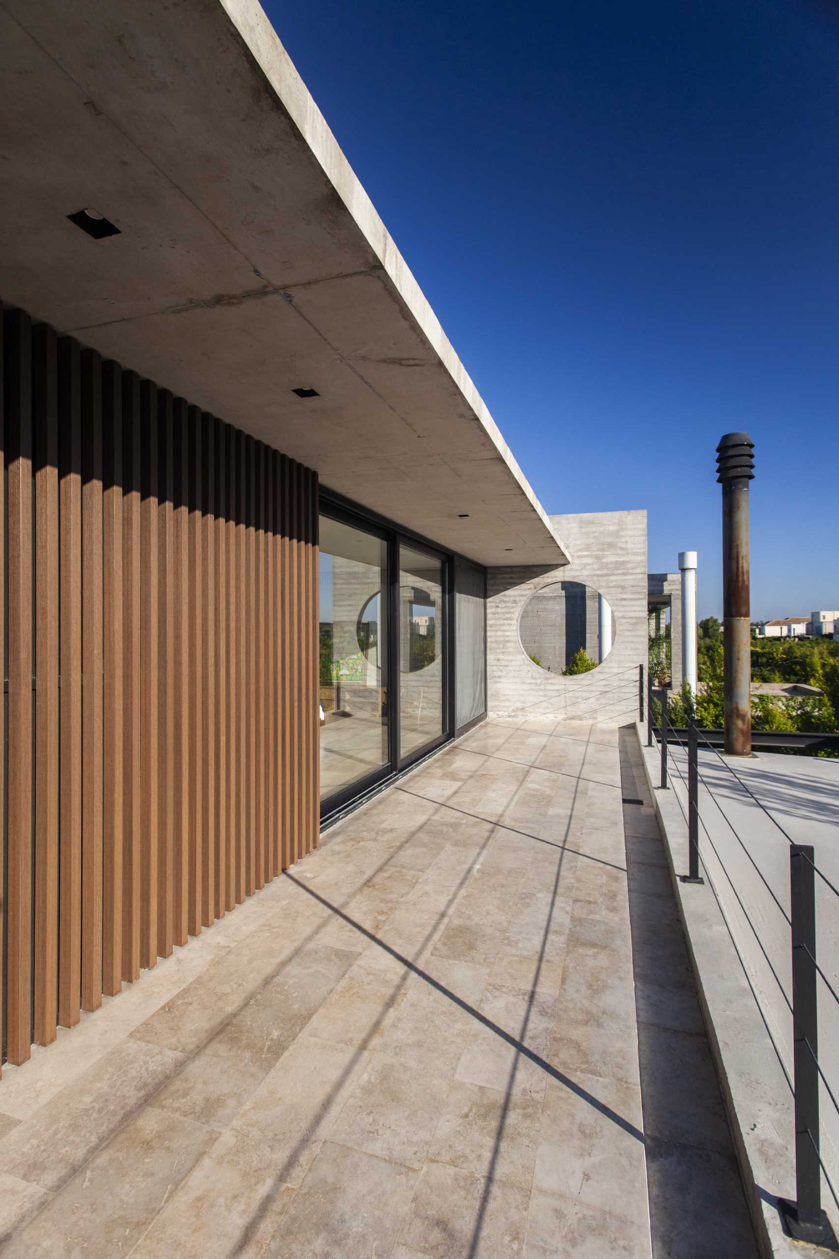 A modern home with a balcony that includes a concrete wall with a round cut-out.