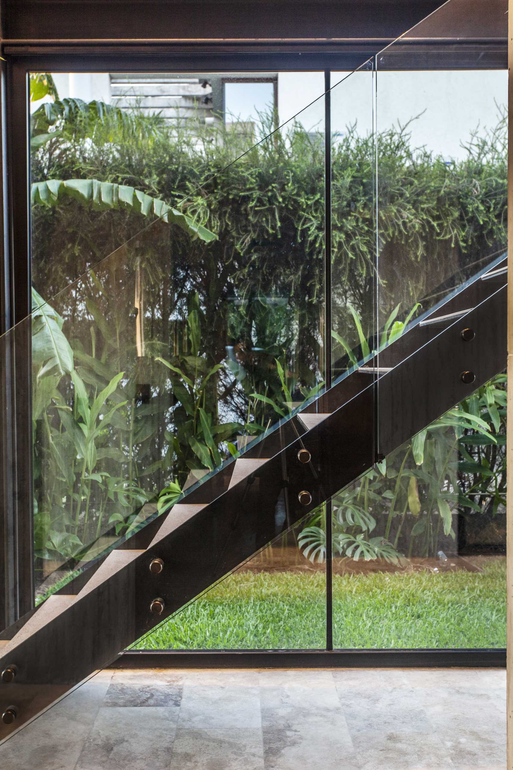 Một ngôi nhà hiện đại với cầu thang màu đen tối giản và lan can bằng kính.