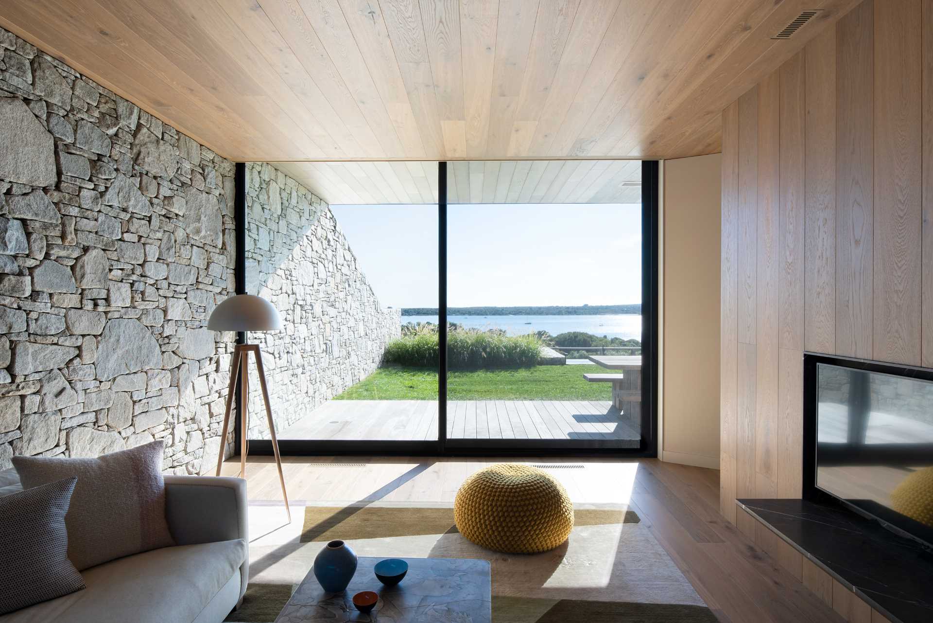 A modern living room with a stone wall that travels from the interior through to the exterior.