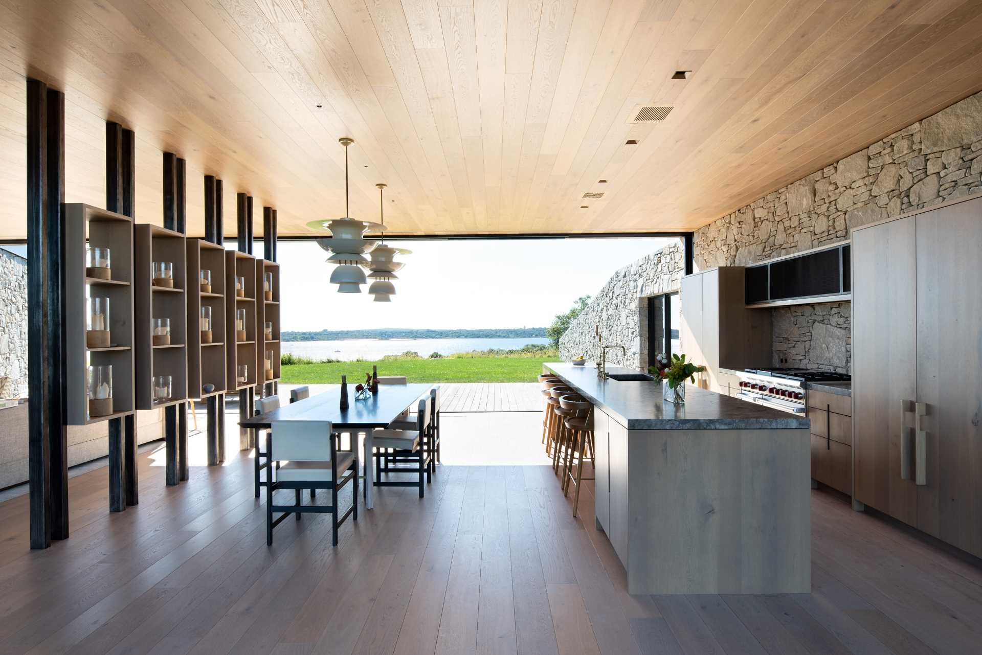 A modern kitchen with a stone wall that travels from the interior to the exterior of the home.