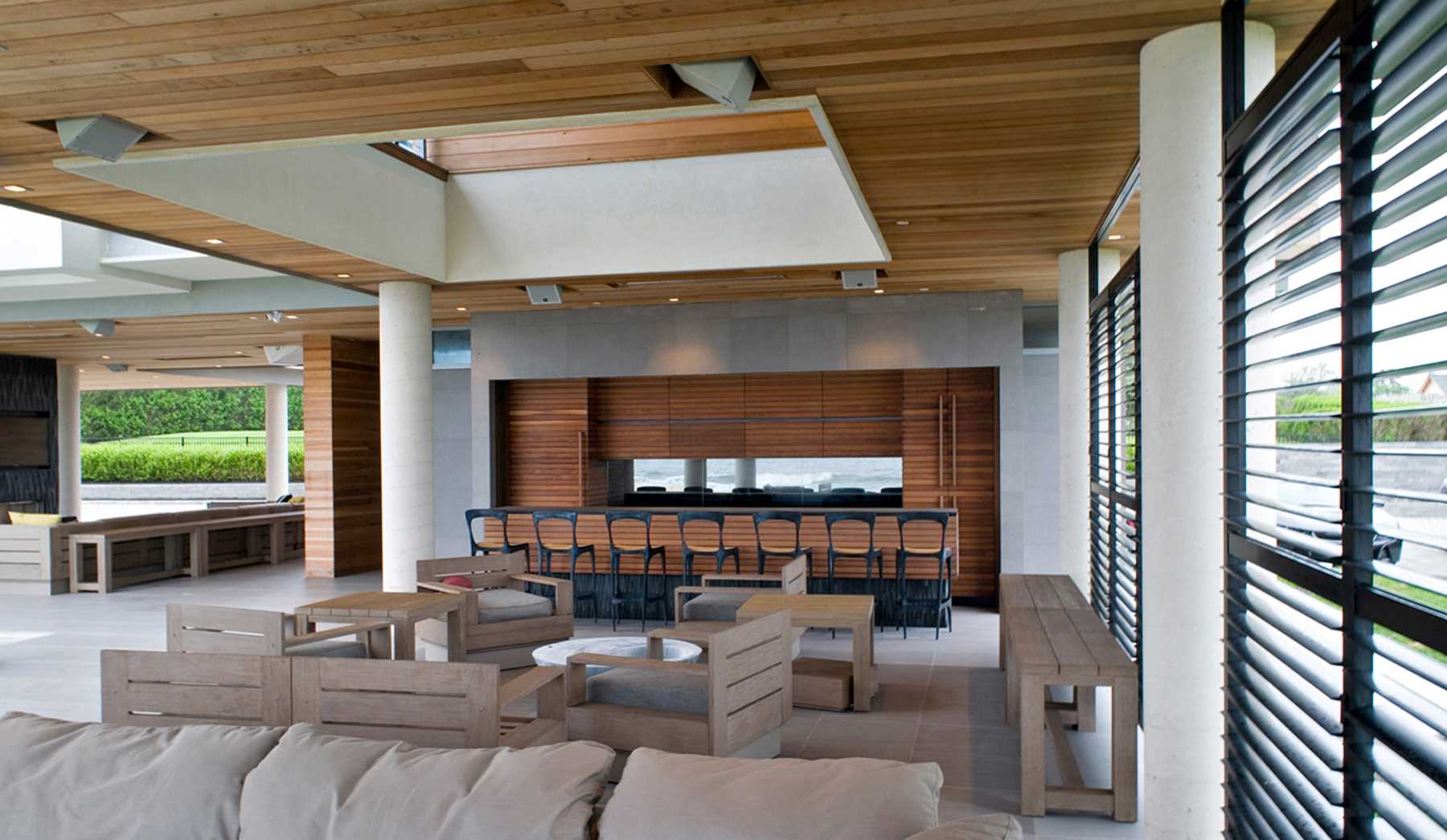 یک خانه مدرن ضد طوفان با یک منطقه سرگرمی در فضای باز گسترده که شامل یک چمن، است،، آشپزخانه در فضای باز، و مناطق نشیمن سرپوشیده است.
