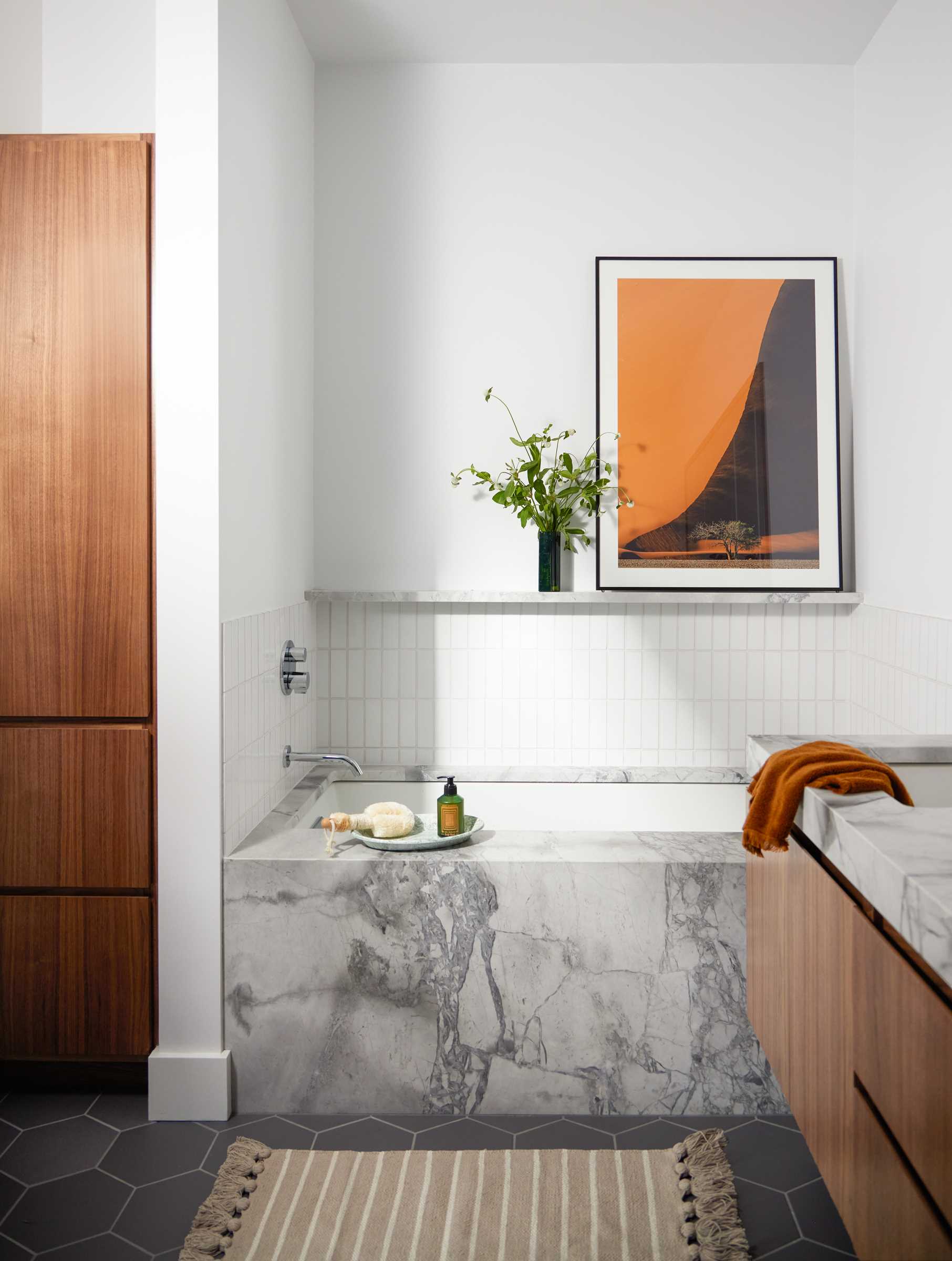 The updated primary bathroom includes Dolomite countertop and bathtub surround, while a new wood vanity increases storage, and vertical subway tiles line the walls.