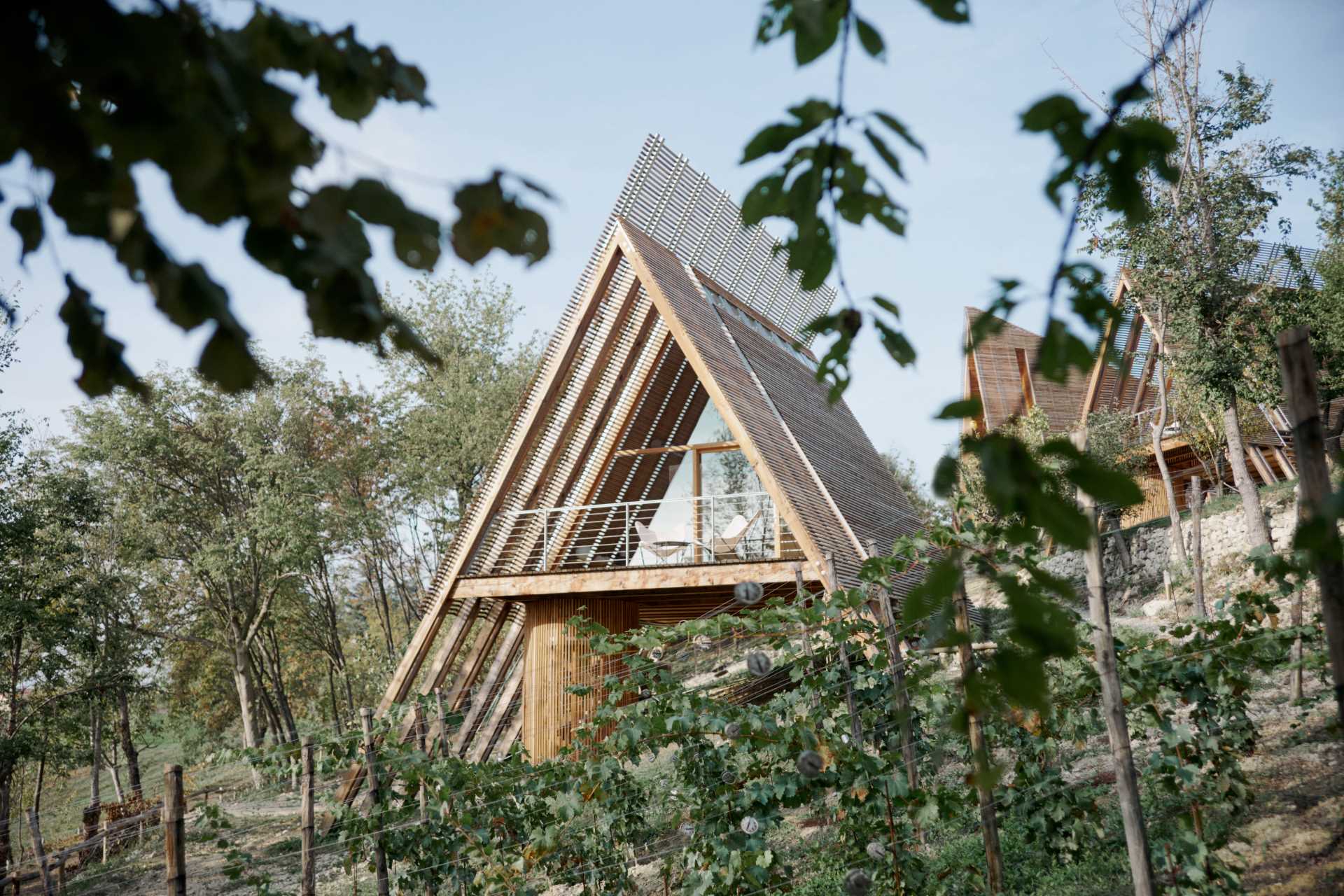 This modern A-frame cabin is raised off the ground, a construction approach that responds to the sloping land of the site.