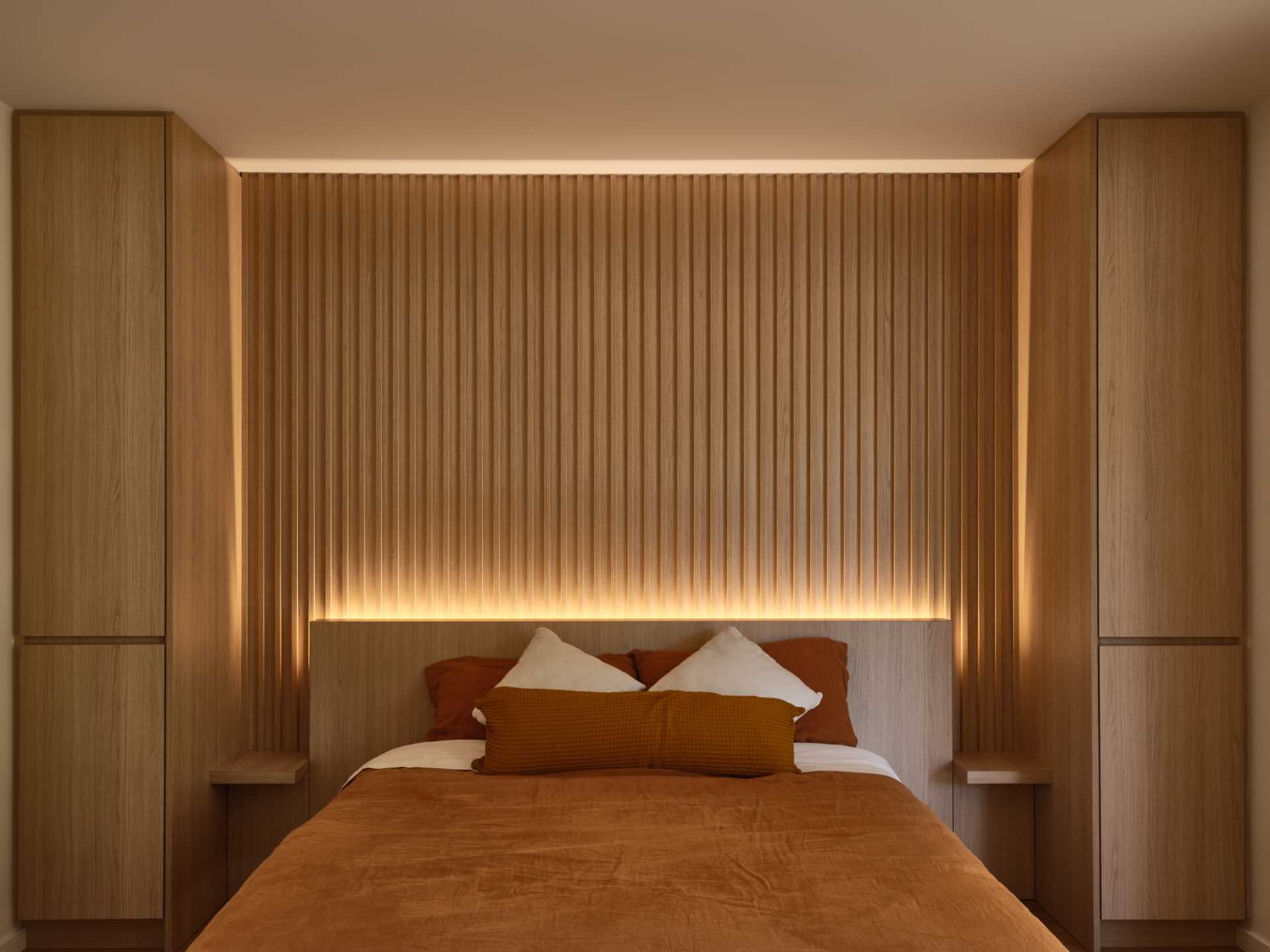A modern wood-lined bedroom with hidden lighting.