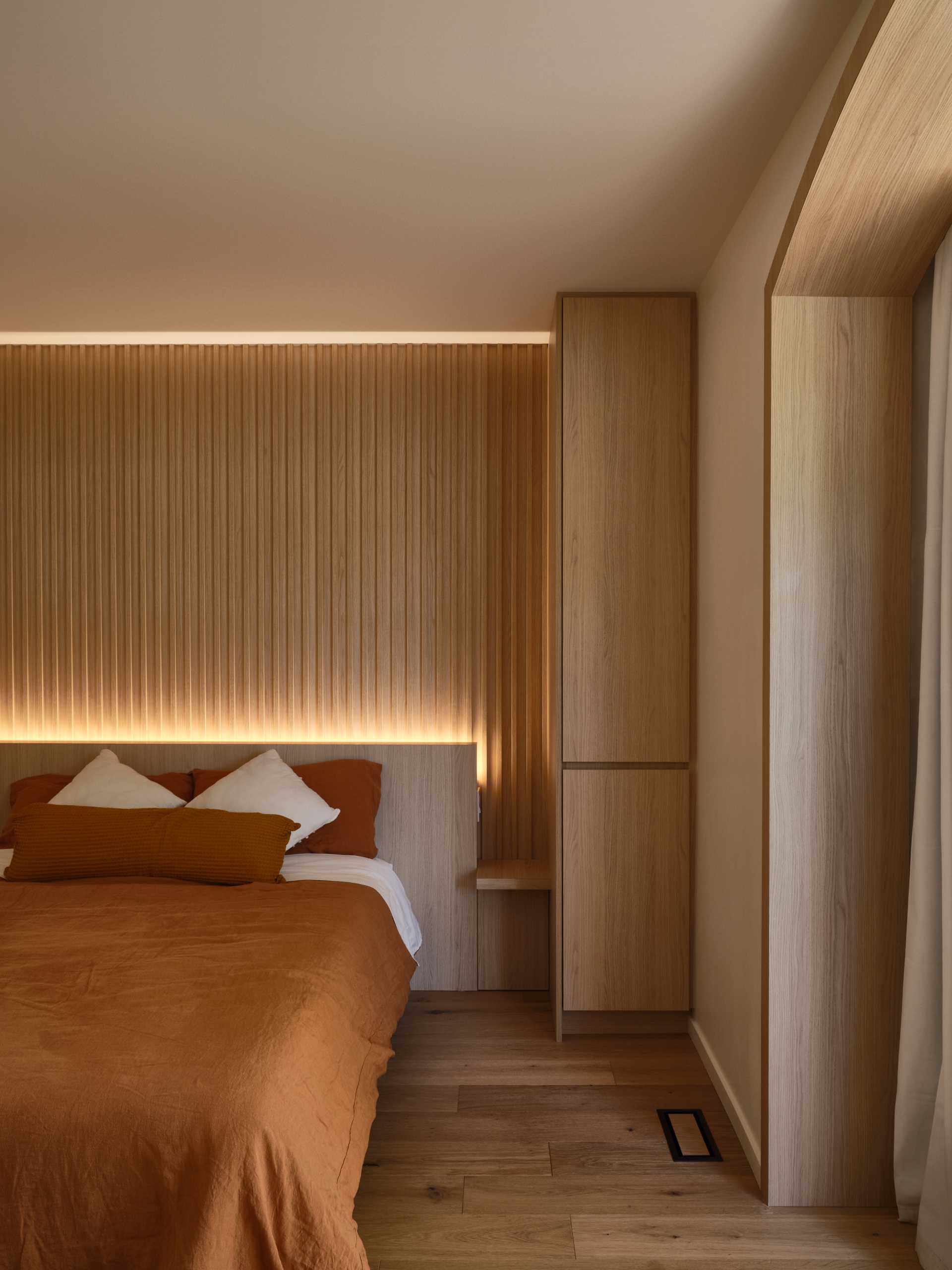 A modern wood-lined bedroom with hidden lighting.