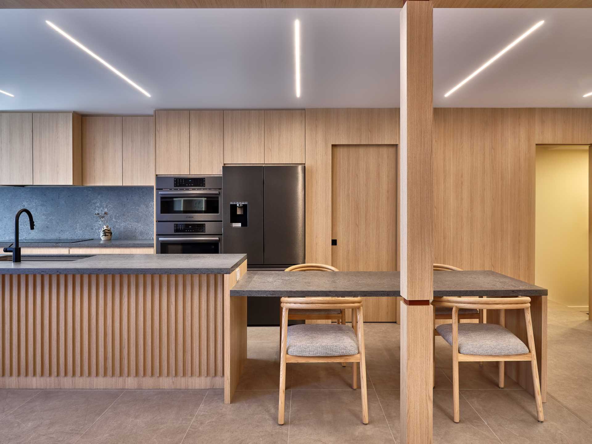 A modern kitchen with wooden pocket doors lead to the hidden pantry, a dog shower, and a separate entrance to the garage.