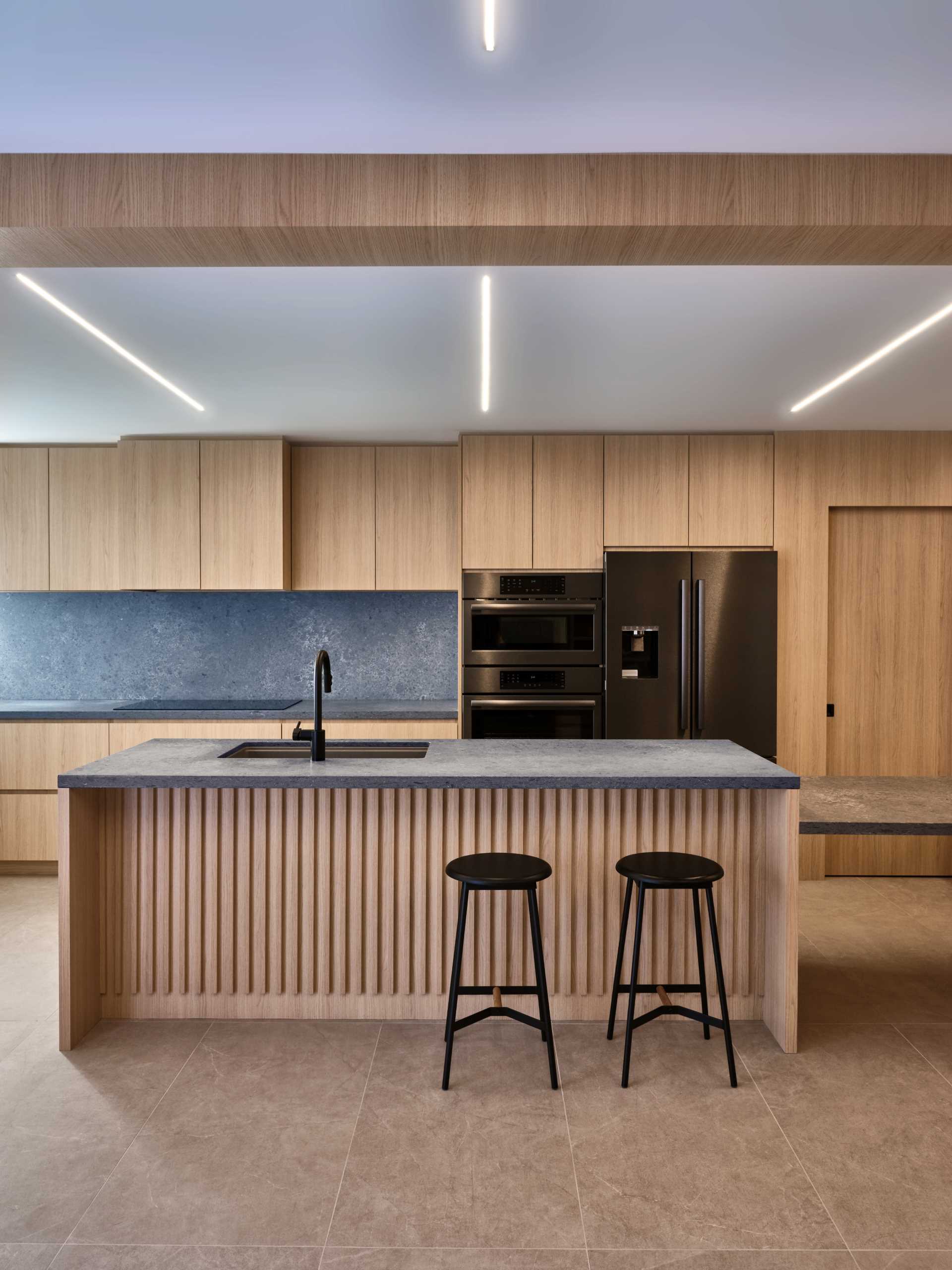 A modern kitchen with wooden pocket doors lead to the hidden pantry, a dog shower, and a separate entrance to the garage.