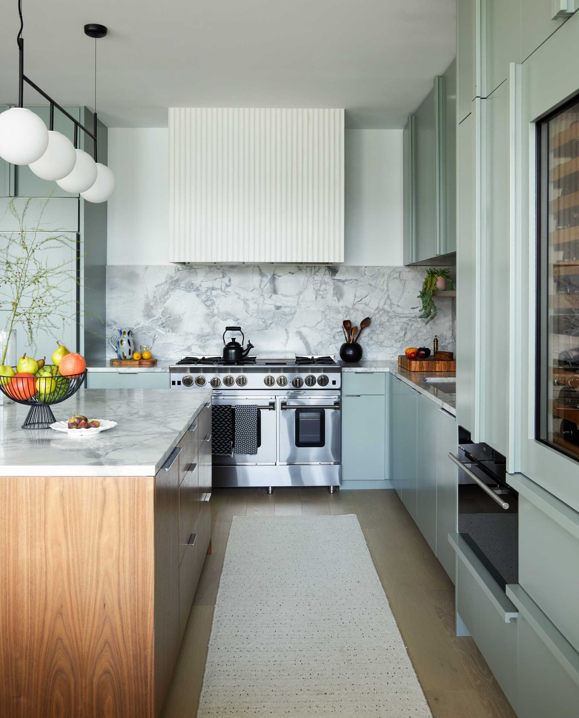 The remodeled kitchen and dining area includes a lighter palette overall, with white oak flooring, soft, creamy green cabinetry in the color of Benjamin Moore’s Rushing River, and Dolomite countertop and backsplash.