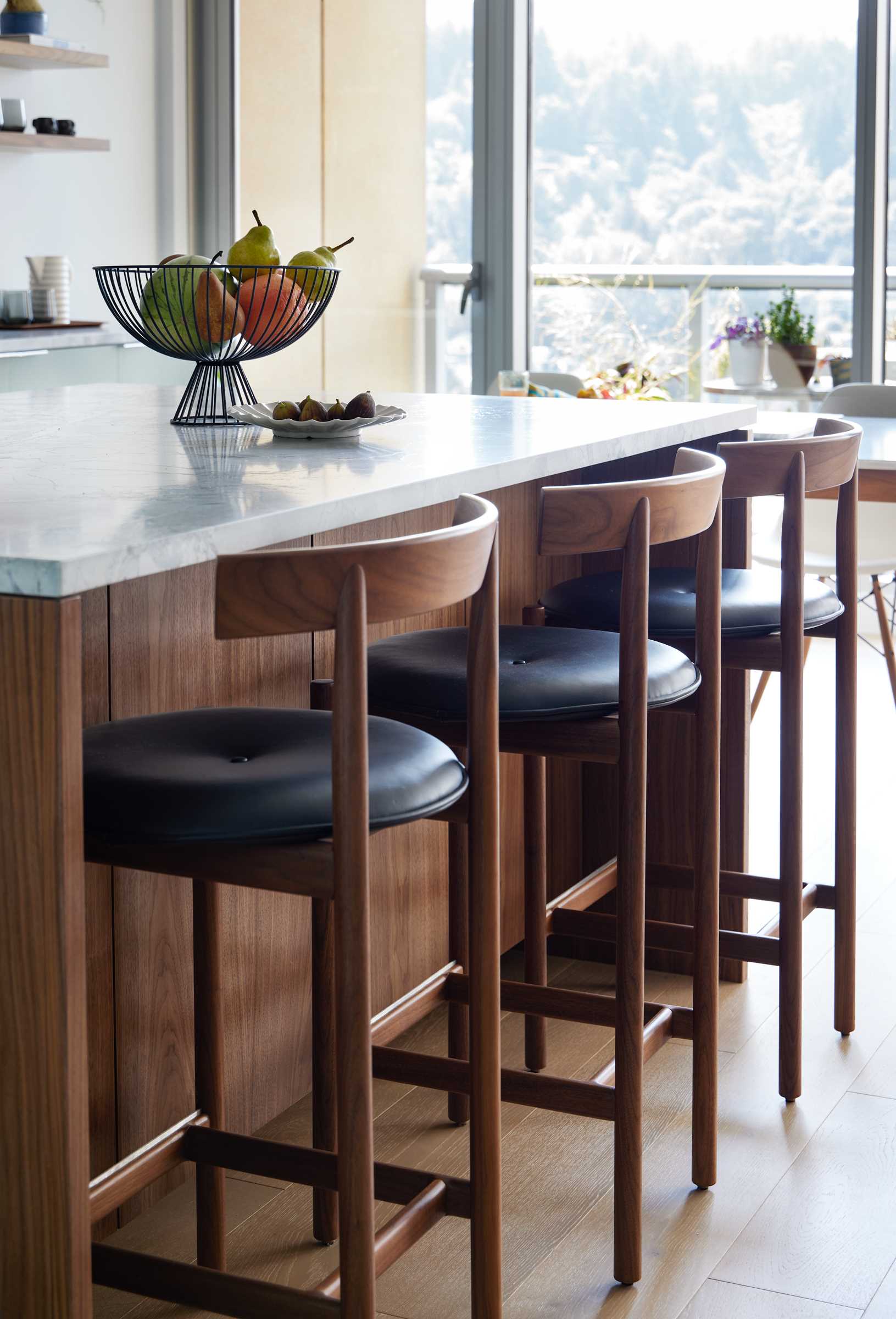 A new kitchen island and custom sideboard show off rich, natural walnut elements, while a Dolomite slab covers the kitchen island and countertops, as well as the backsplash.