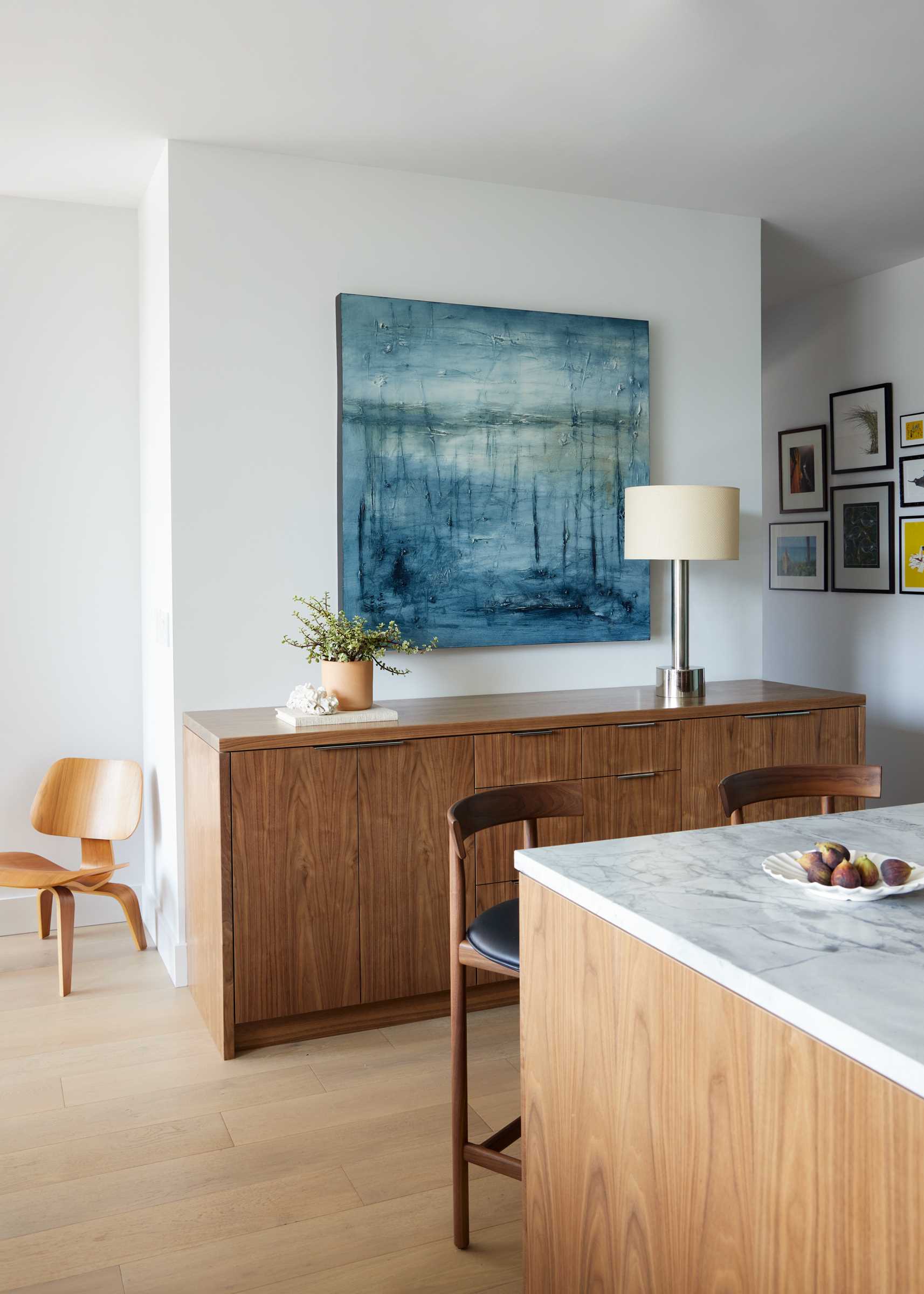 A new kitchen island and custom sideboard show off rich, natural walnut elements, while a Dolomite slab covers the kitchen island and countertops, as well as the backsplash.