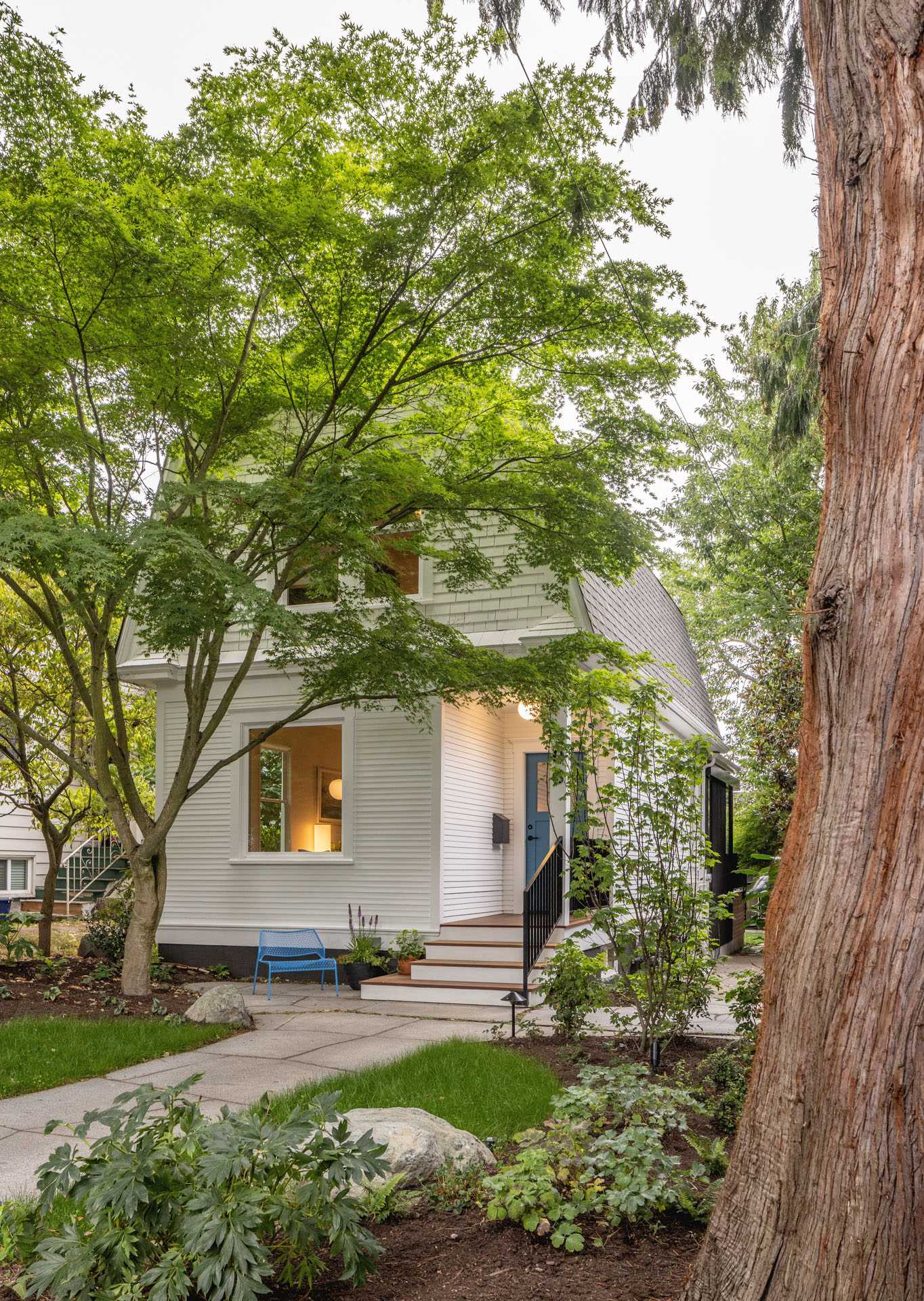 A remodeled 1907 cottage with a blue front door and stone patio.