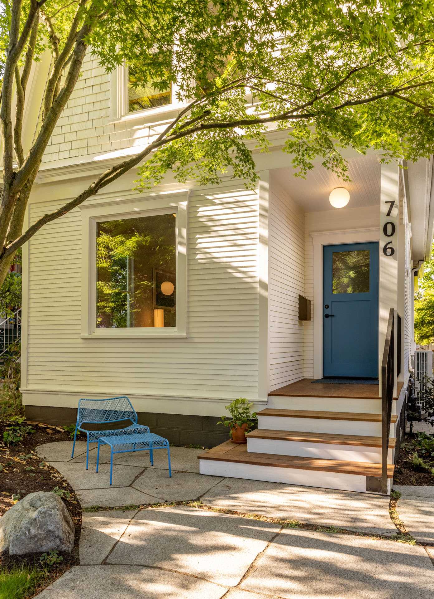 A remodeled 1907 cottage with a blue front door and stone patio.