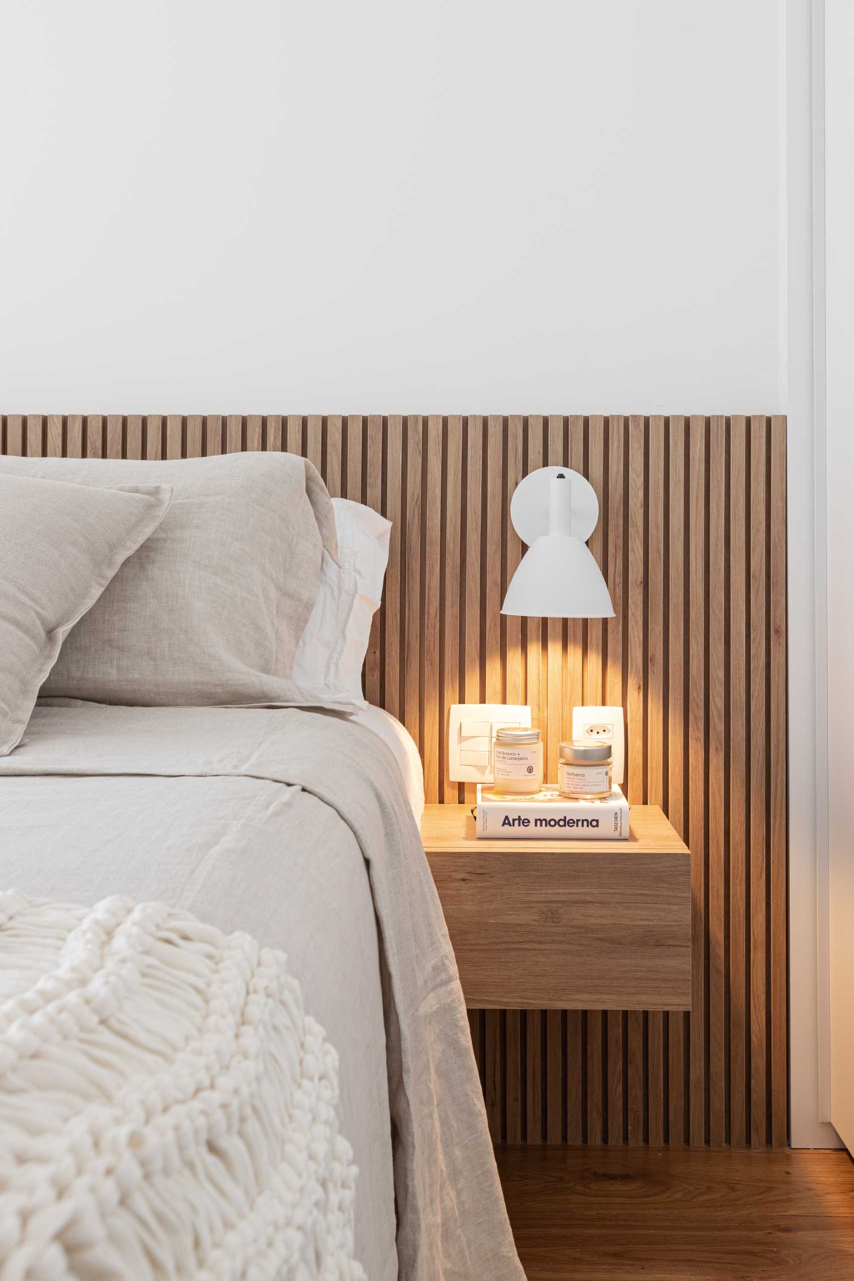 This modern bedroom includes hidden lighting behind the wood headboard, as well as wall-mounted bedside lamps and floating bedside tables.