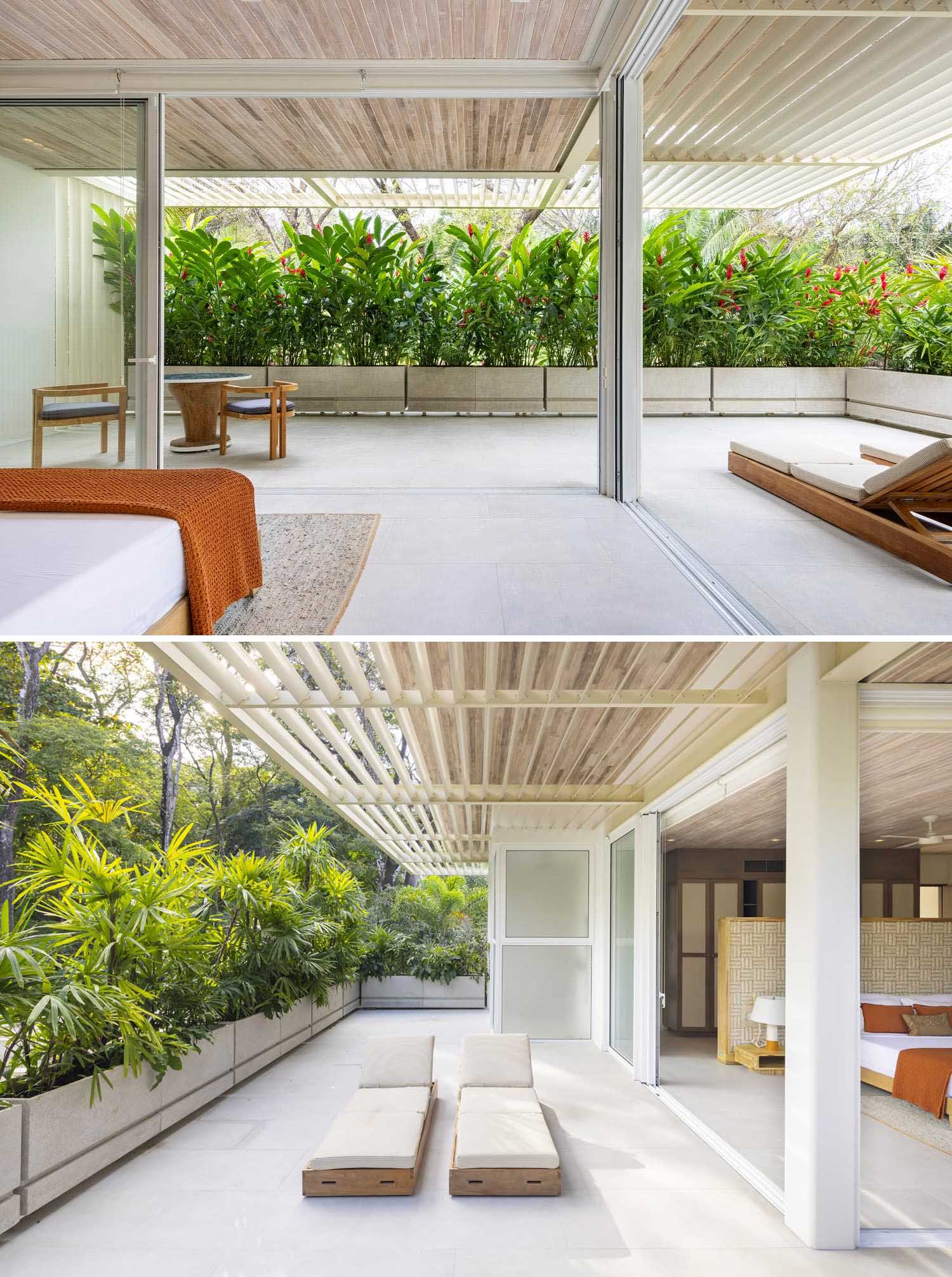 A modern bedroom that opens to an outdoor space with planter boxes filled with tropical plants.