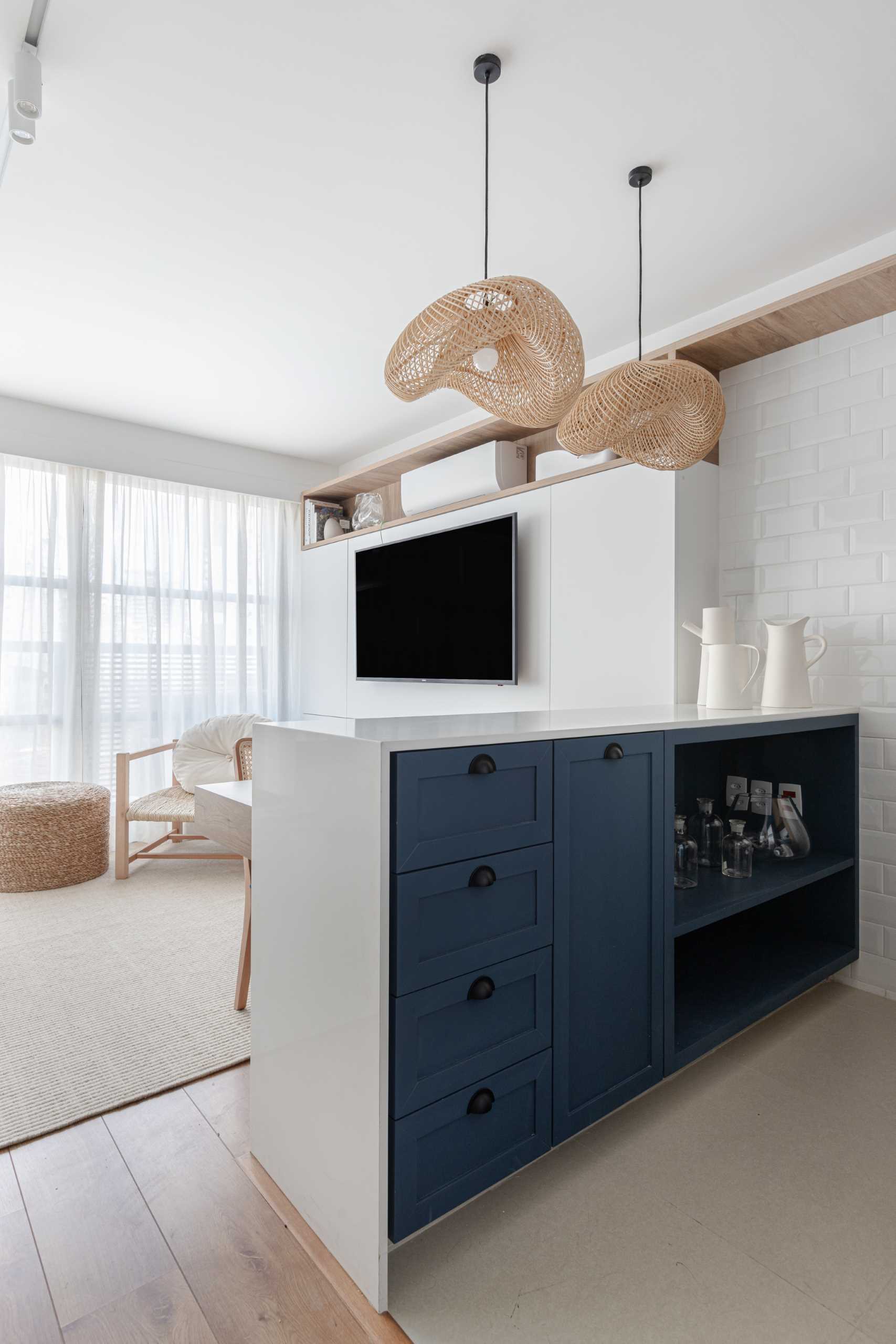 This small kitchen features wood and blue cabinets, white subway tile, and a pair of woven pendant lights.