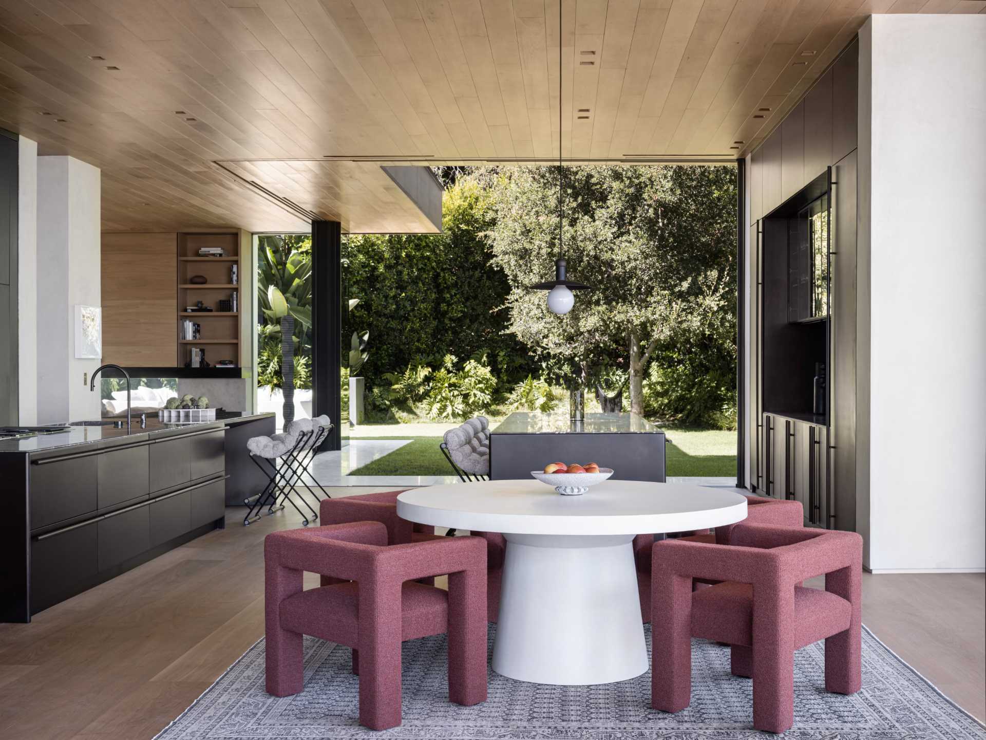 A casual dining area with a round table and colorful chairs, that's anchored in the space by a square rug.