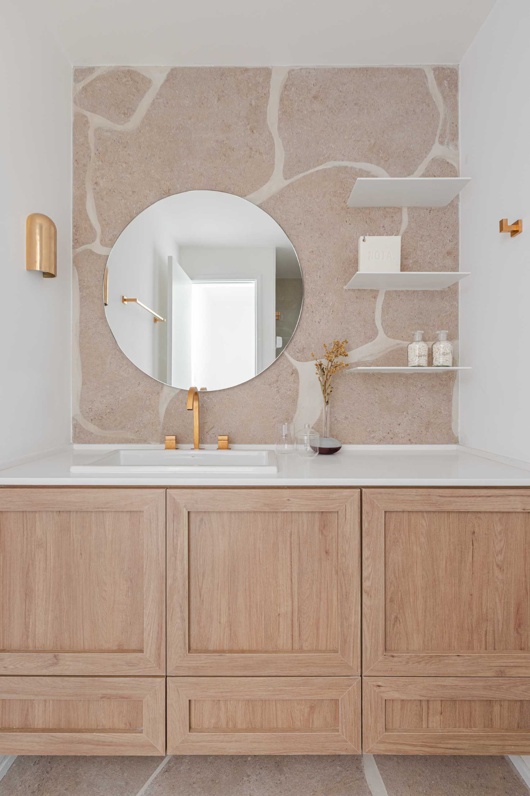 A modern bathroom has a neutral color palette with a wood vanity, a white countertop, and floating shelves.