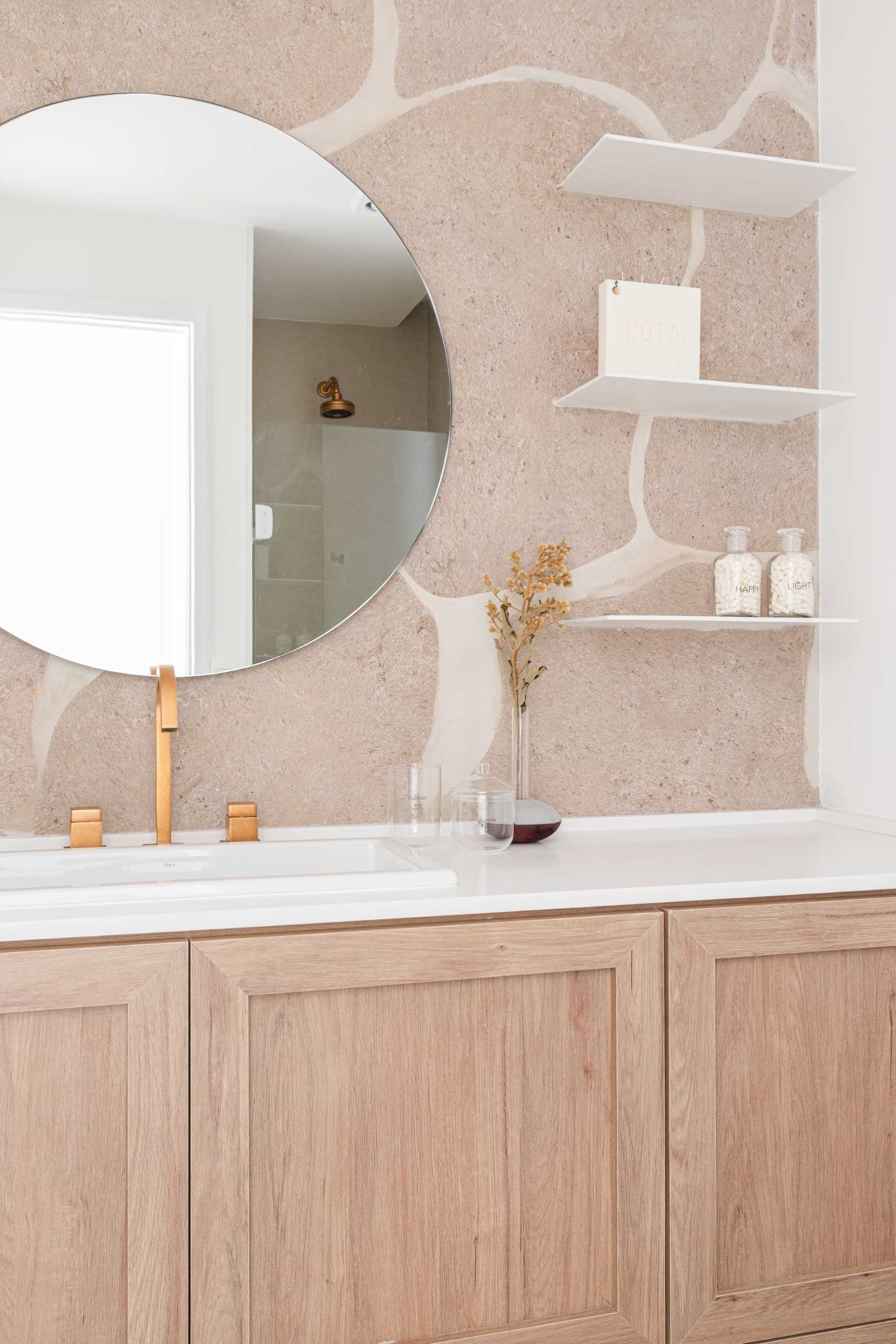 A modern bathroom has a neutral color palette with a wood vanity, a white countertop, and floating shelves.