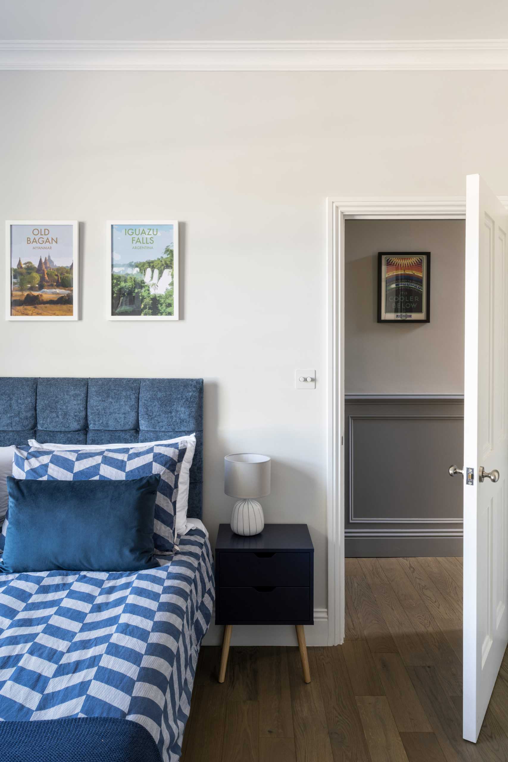 A neutral bedroom with a blue headboard and bedding that add a pop color.