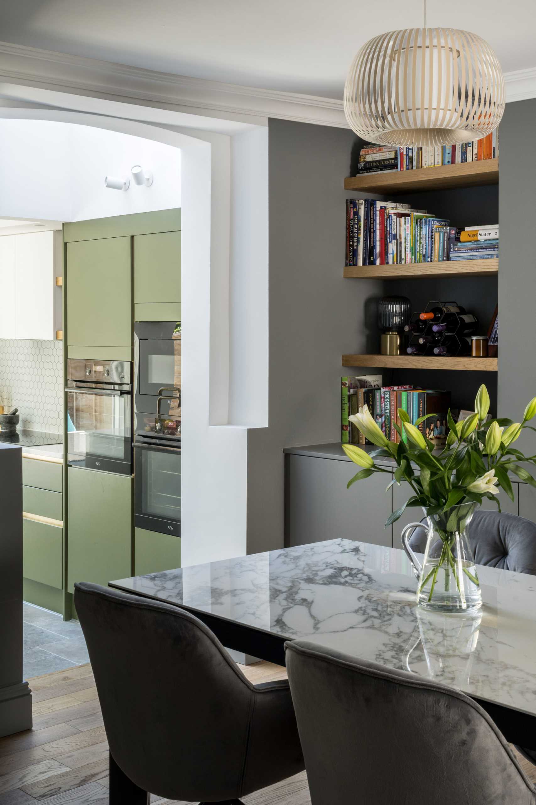 A contemporary dining room with built-in wood shelving and grey cabinets.