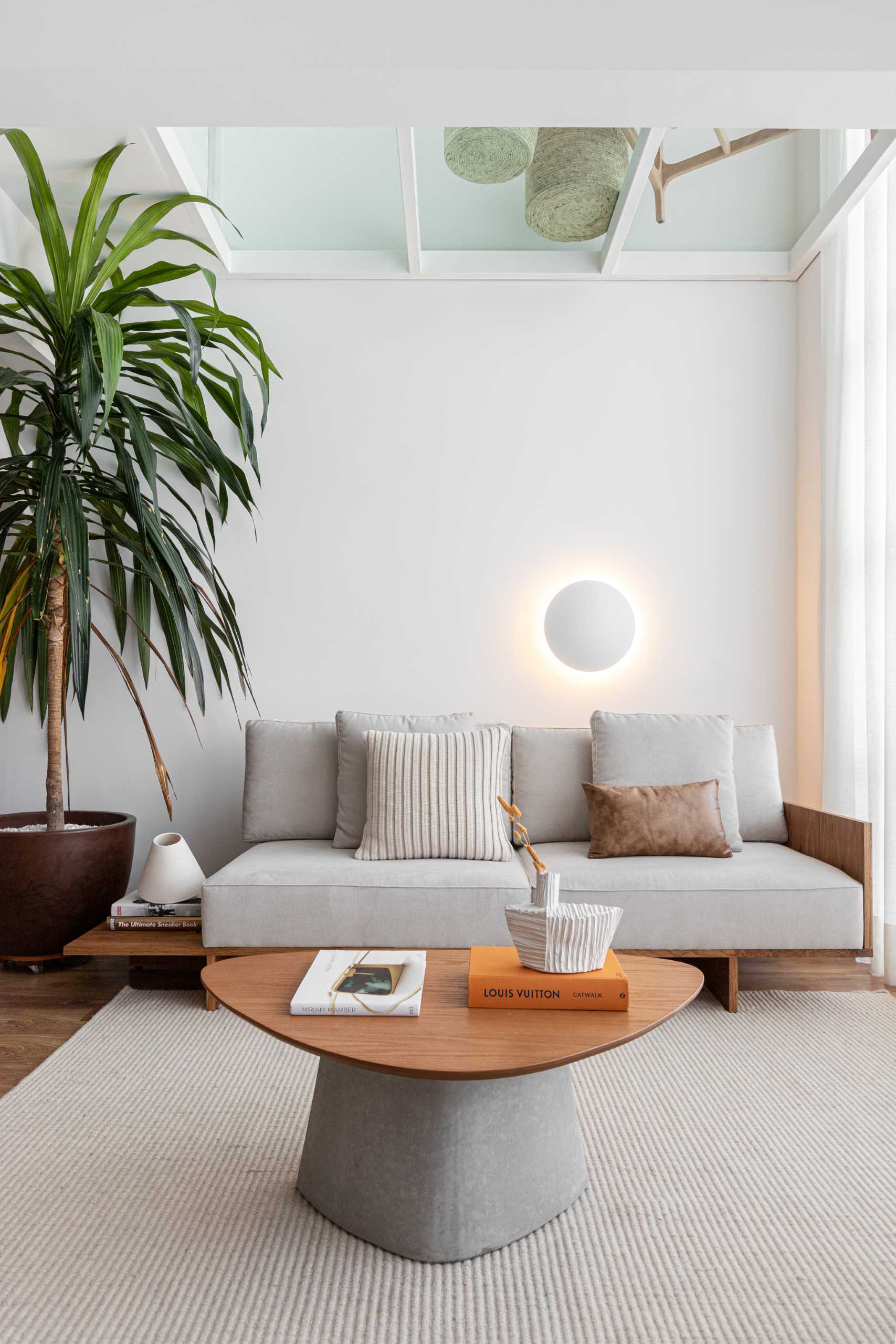 A modern living room with a partial glass ceiling allows natural light to travel throughout the space.