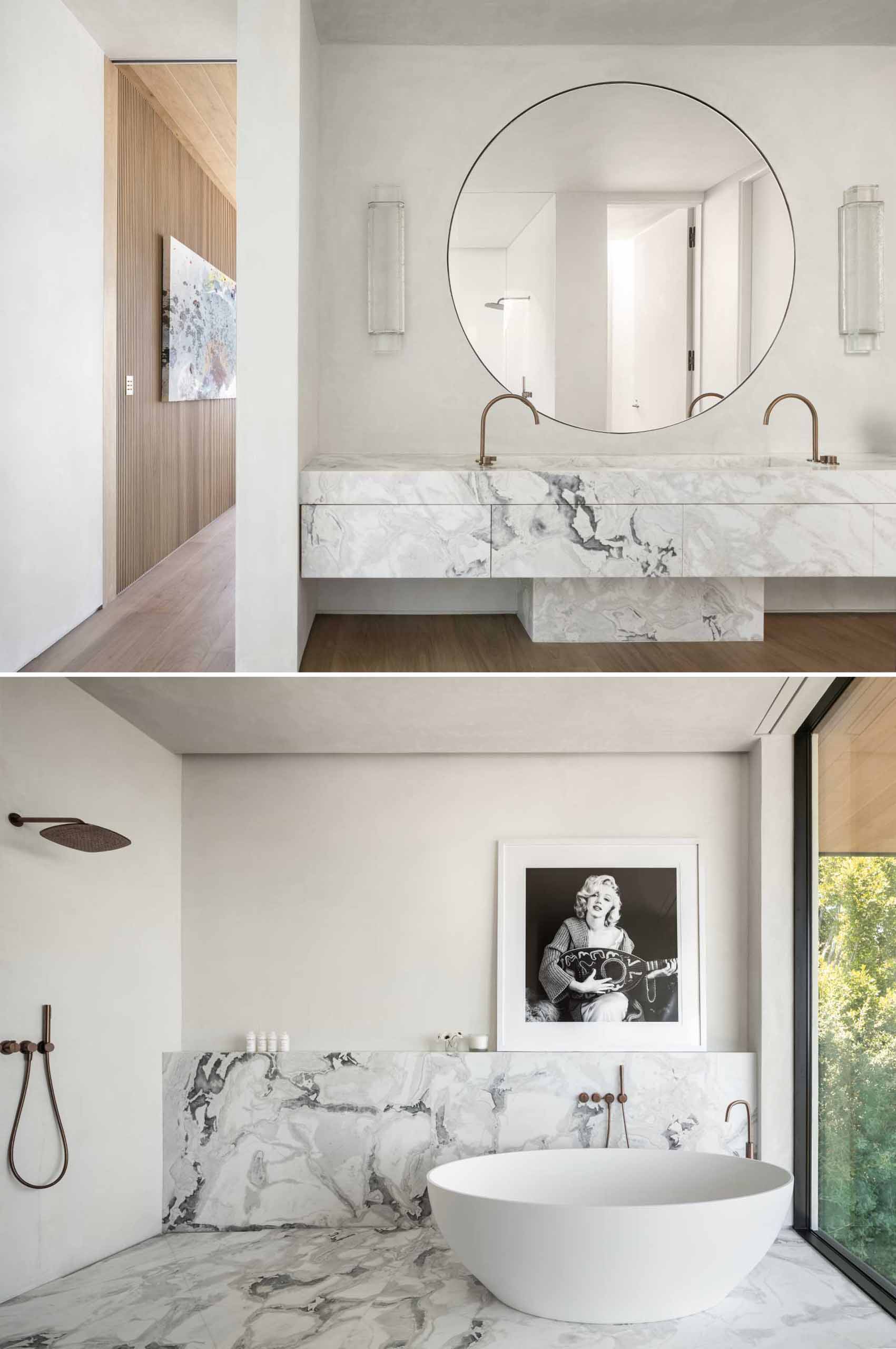 A modern bathroom with a stone vanity, a large round mirror, and a freestanding bathtub.