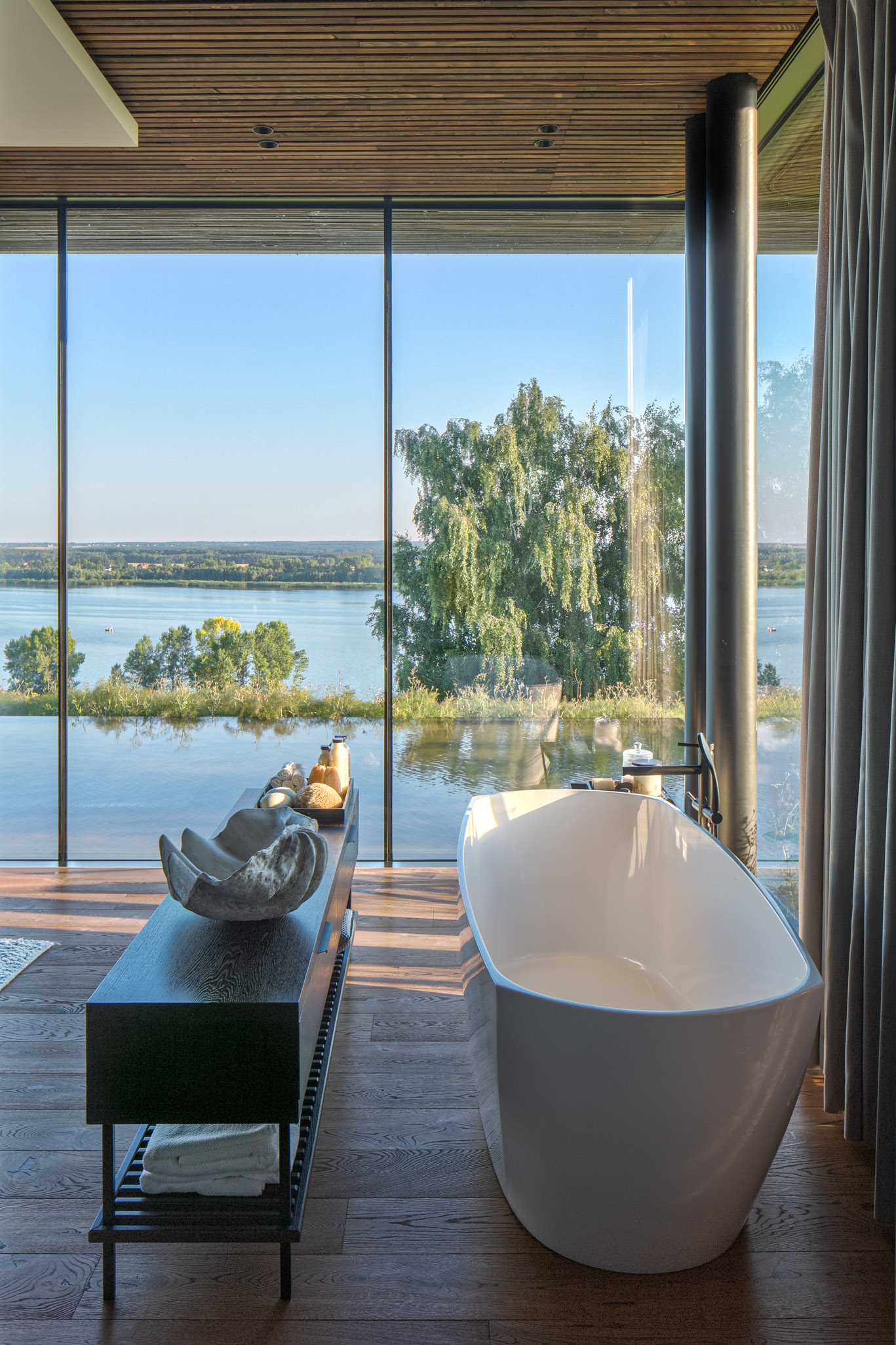 A modern bedroom with floor-to-ceiling windows and a freestanding bathtub.