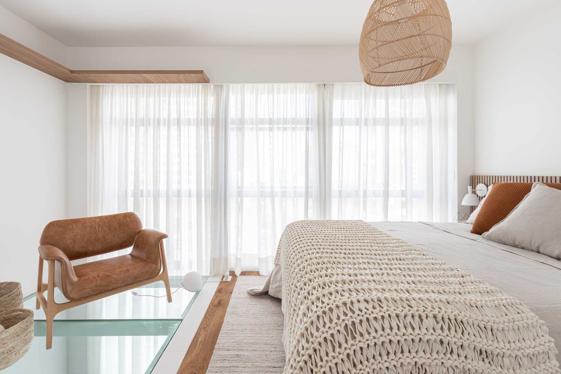 A modern bedroom with a partial glass floor that allows natural light to pass through to the living room below.