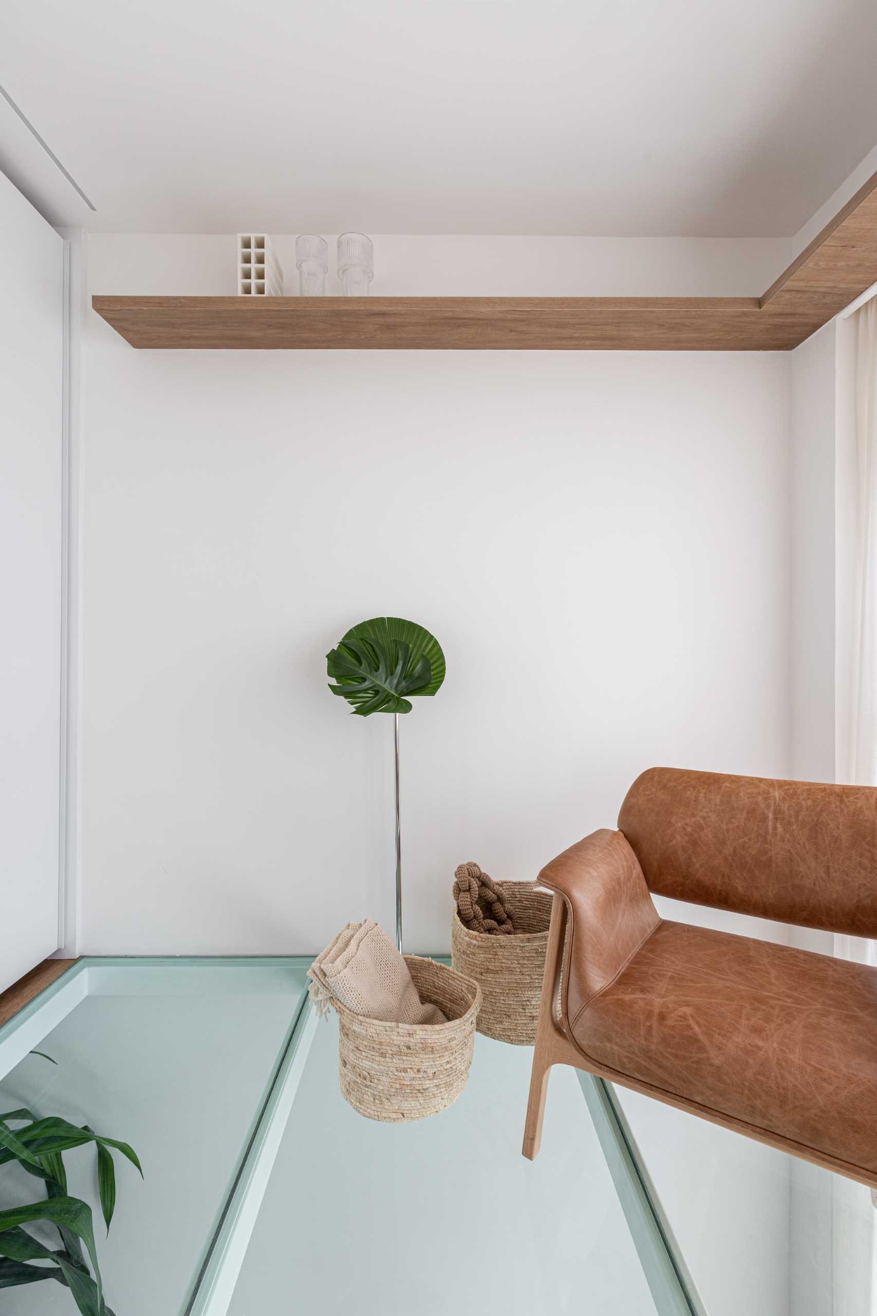 A modern bedroom with a partial glass floor that allows natural light to pass through to the living room below.