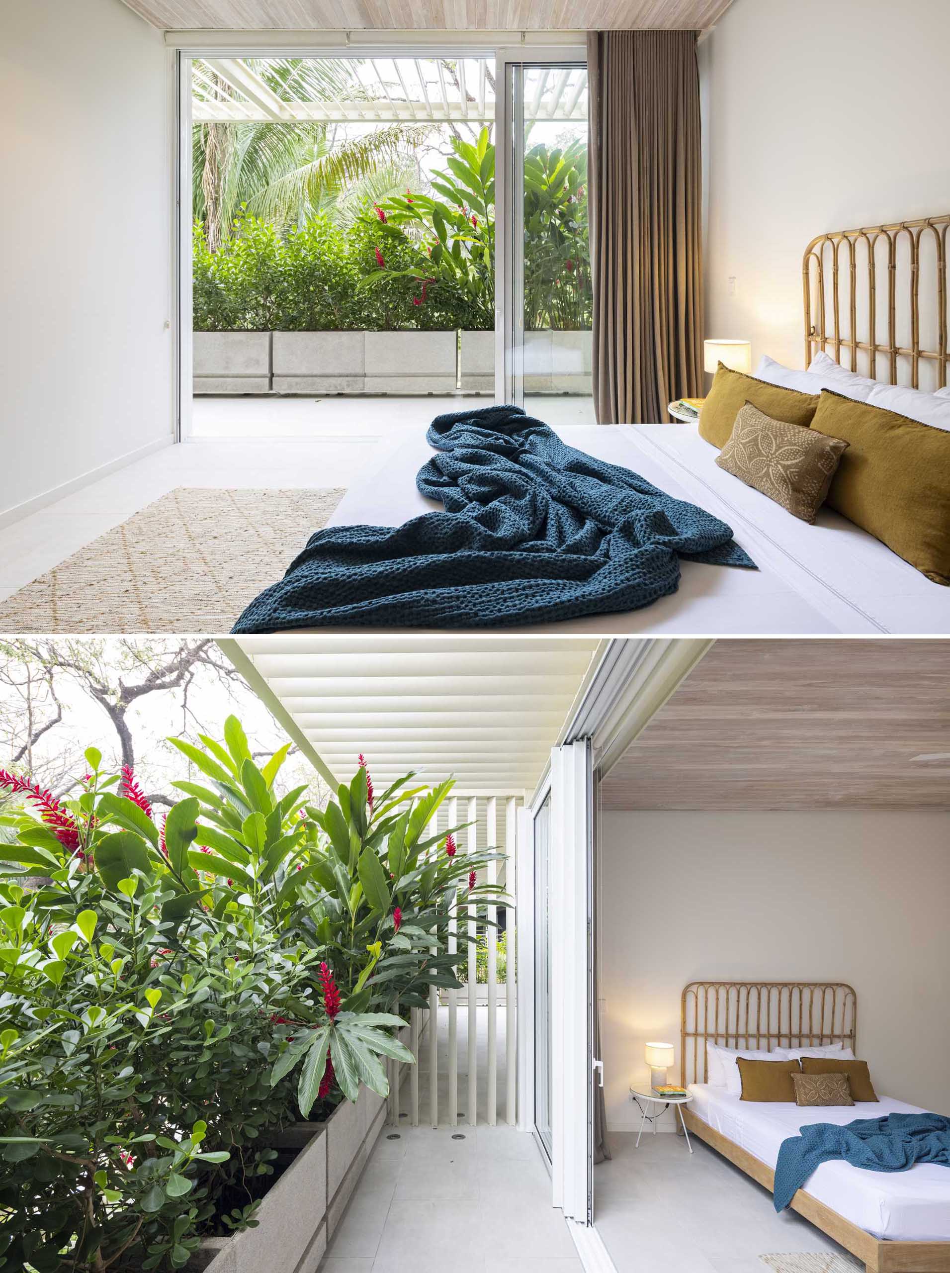 A modern bedroom that opens to an outdoor space with planter boxes filled with tropical plants.