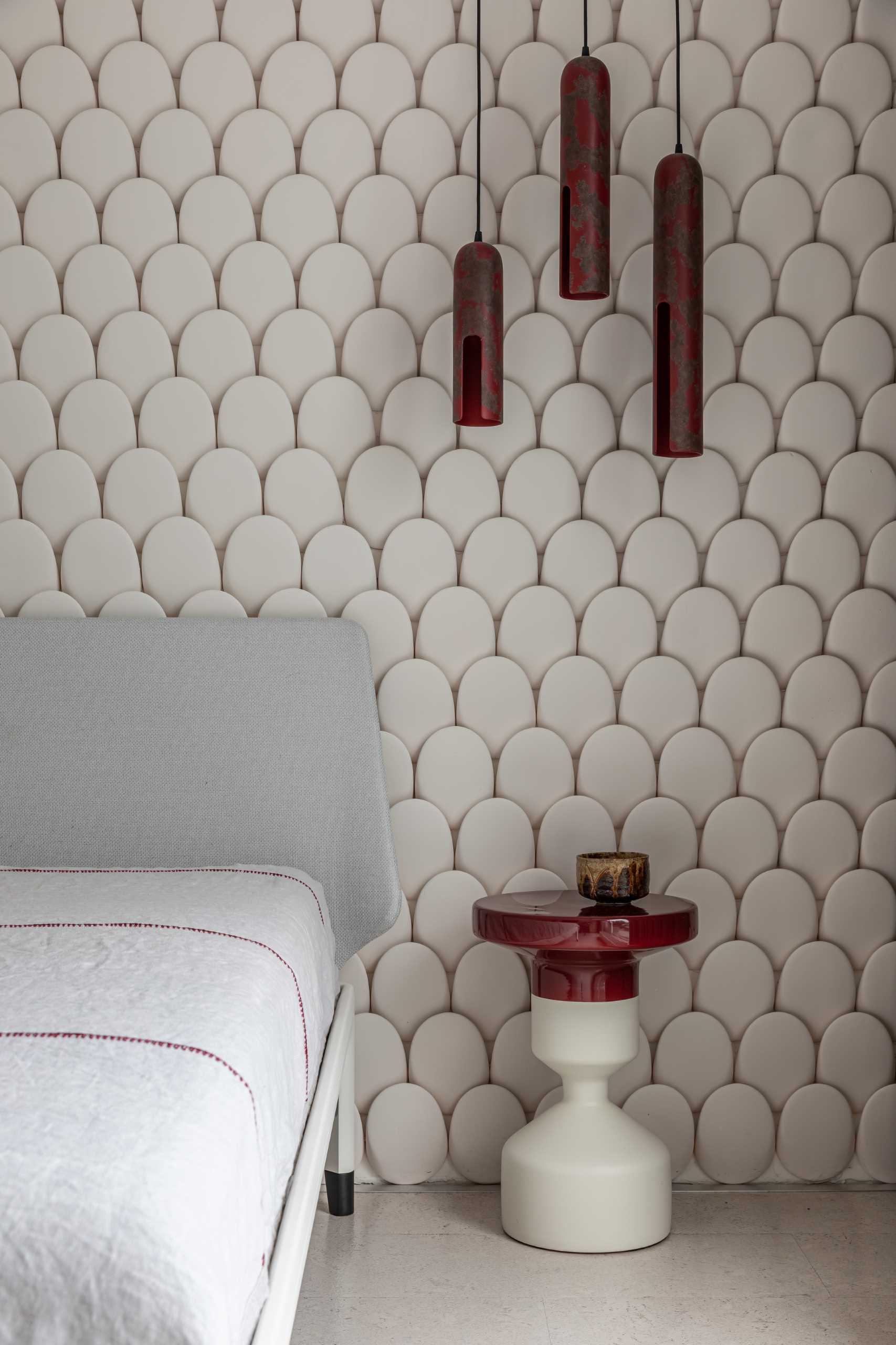 In this modern bedroom, a sculptural wall is covered in individual curved pieces, adding texture and a sense of softness.