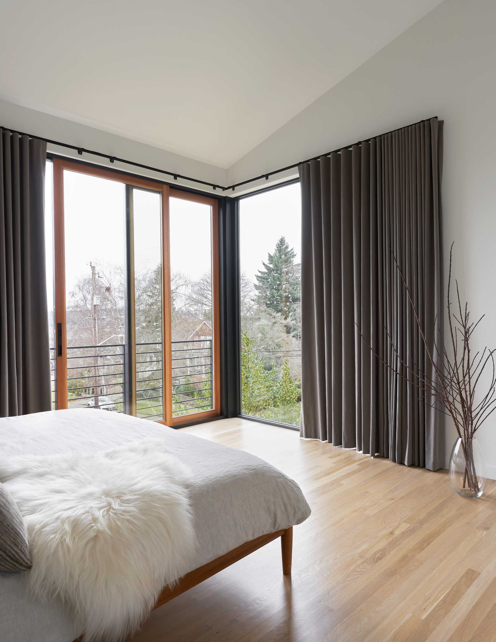 A modern bedroom with large windows that add natural light, while a sliding door can be opened.