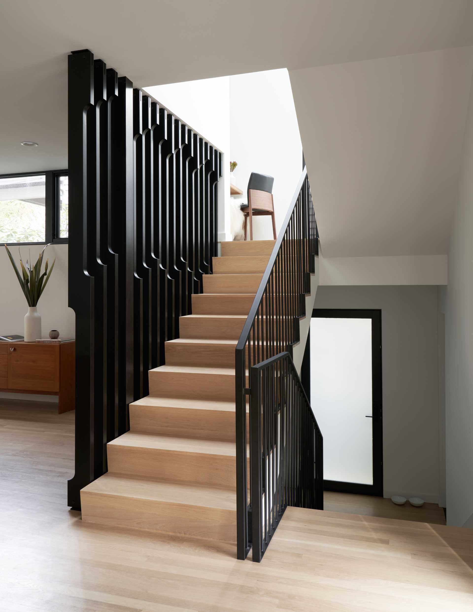 A modern wood and black staircase with a small office nook in the landing.