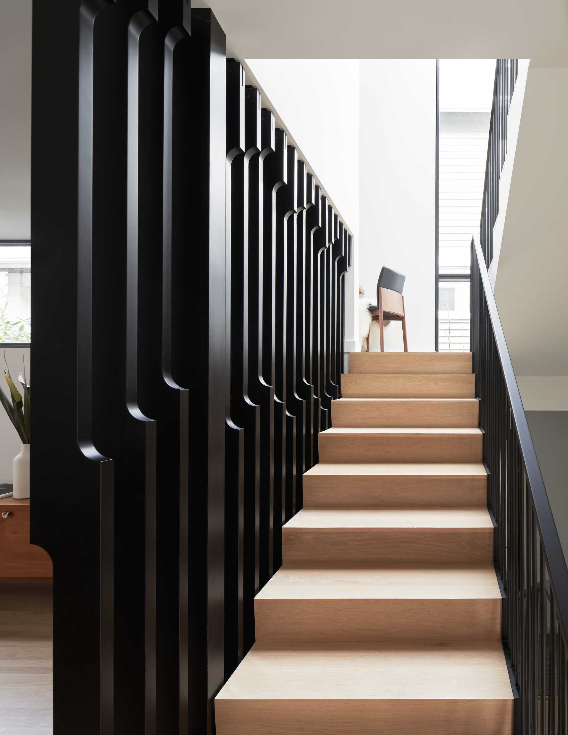 A modern wood and black staircase with a small office nook in the landing.