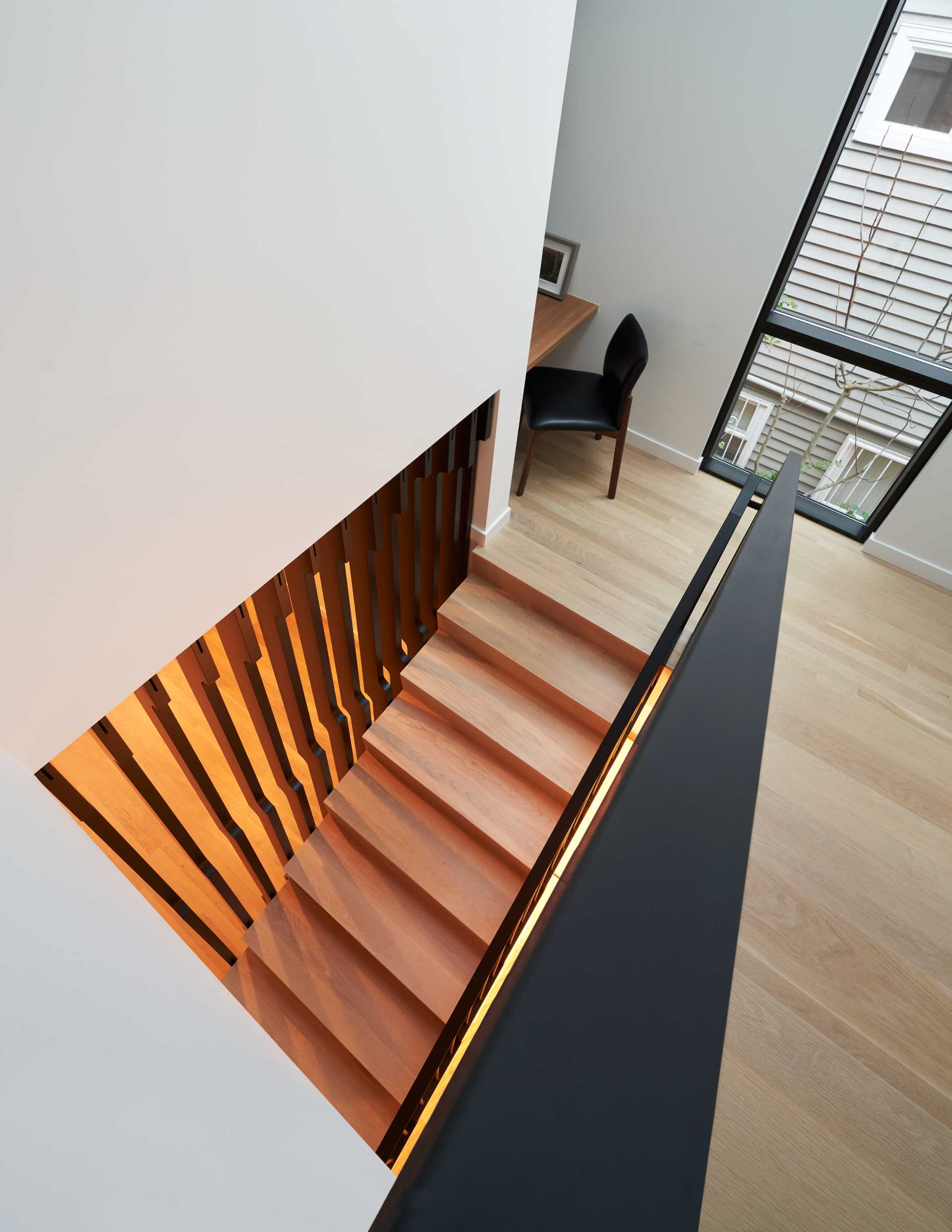 A modern wood and black staircase with a small office nook in the landing.