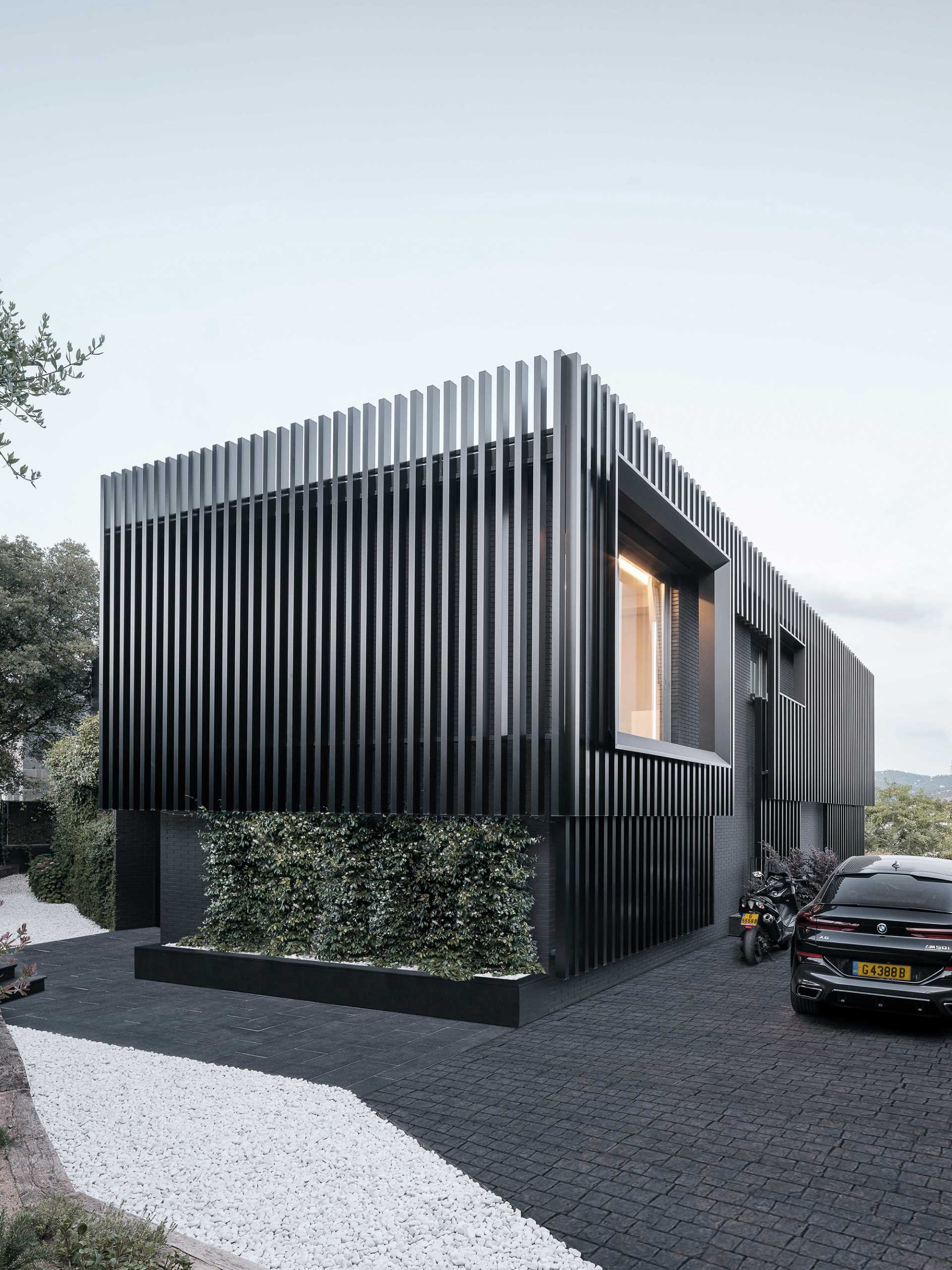 A modern black house has vertical planes that wrap around its exterior, creating a monochromatic appearance.